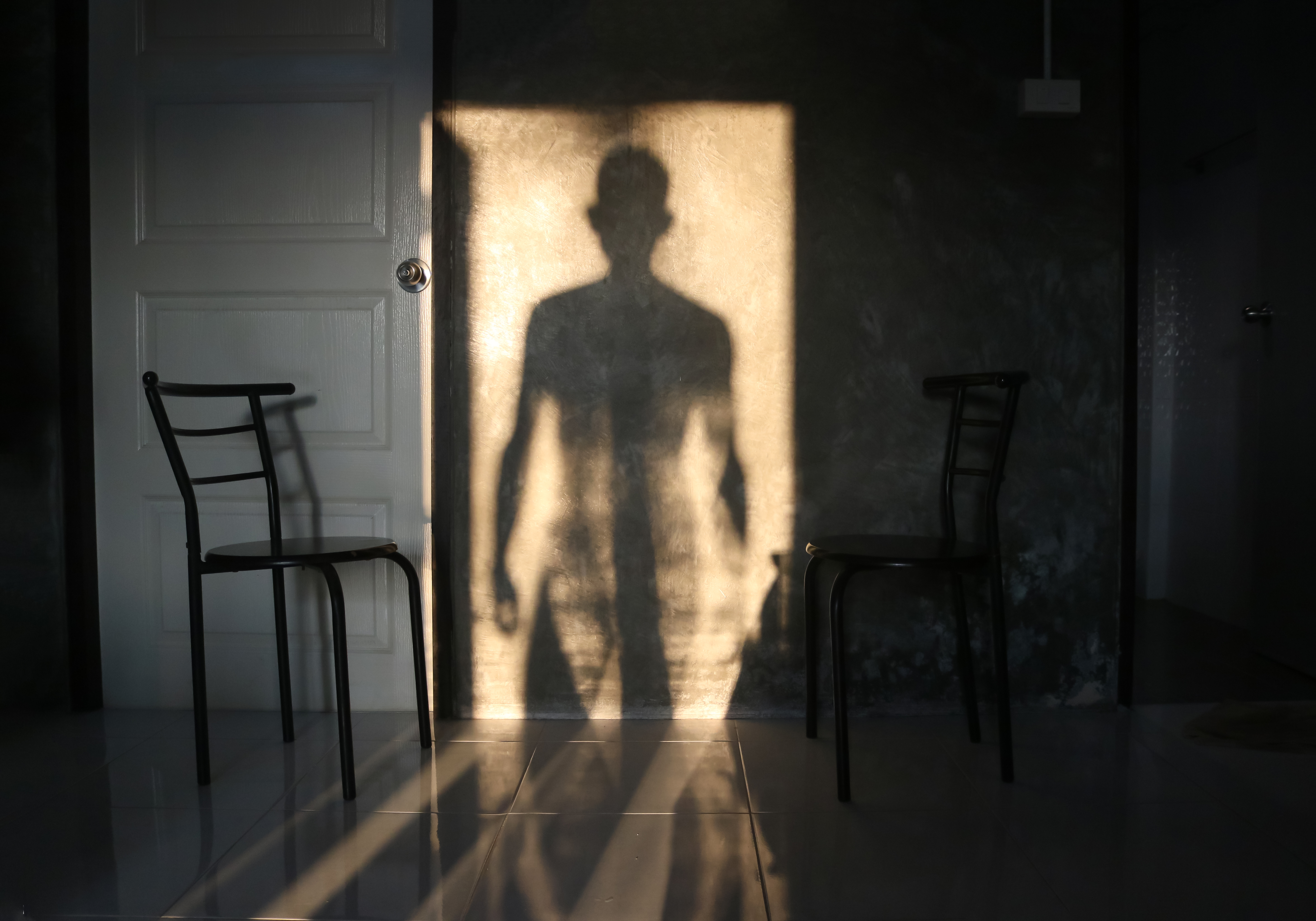 The man's shadow stood in the door on the wall | Source: Shutterstock.com