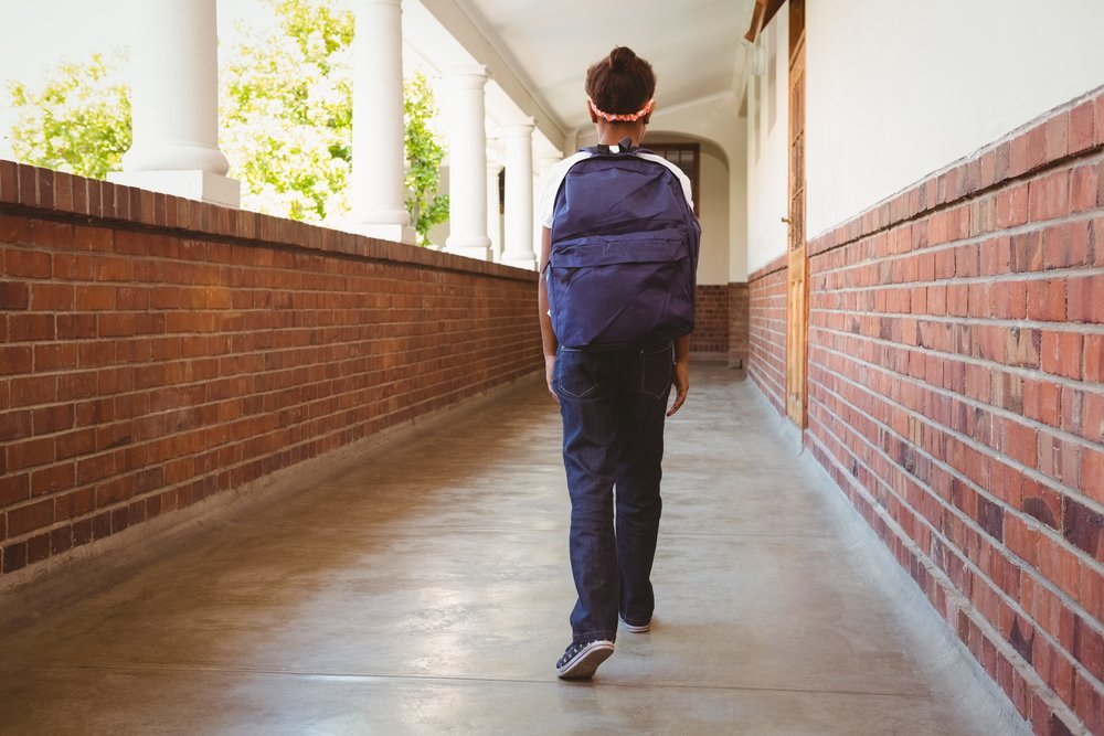 Girl walking in school corridor. | Source: Shutterstock