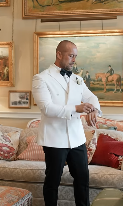 Terry Kavanagh adjusts his watch while wearing a double-breasted white suit and black trousers on his and Erin McGregors wedding day, August 17, 2024 | Source: Instagram/odicci_films