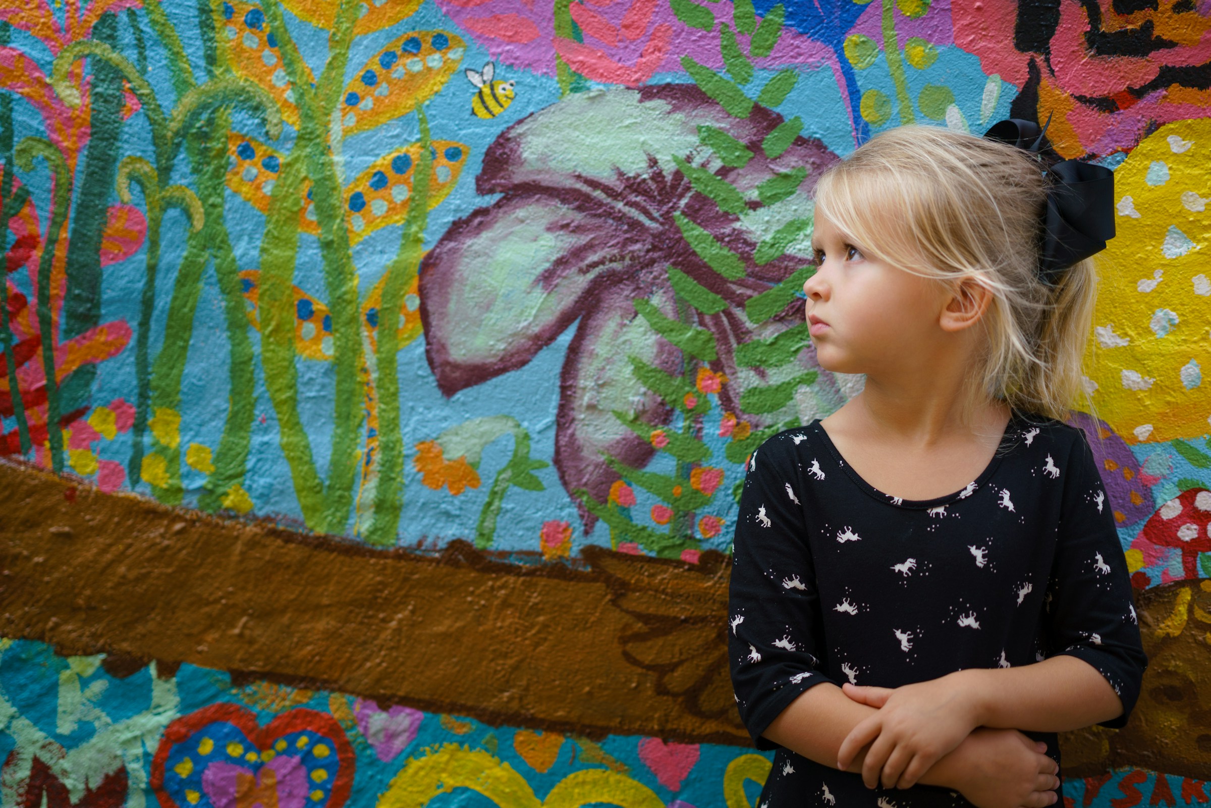 A little girl standing against a floral background | Source: Unsplash
