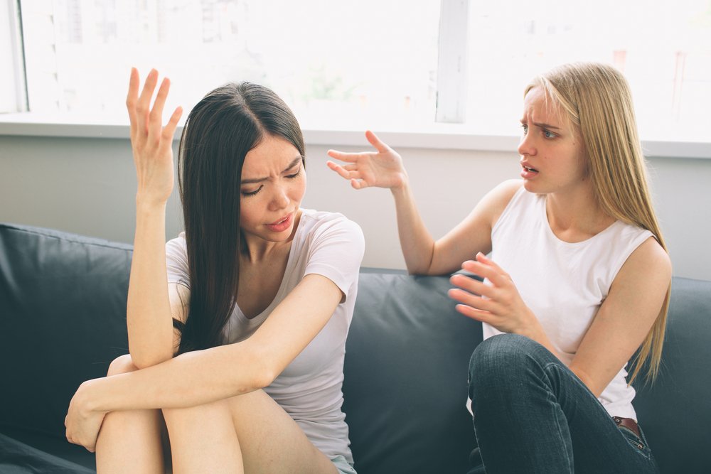 Two women arguing while sitting together on a couch. | Photo: Shutterstock