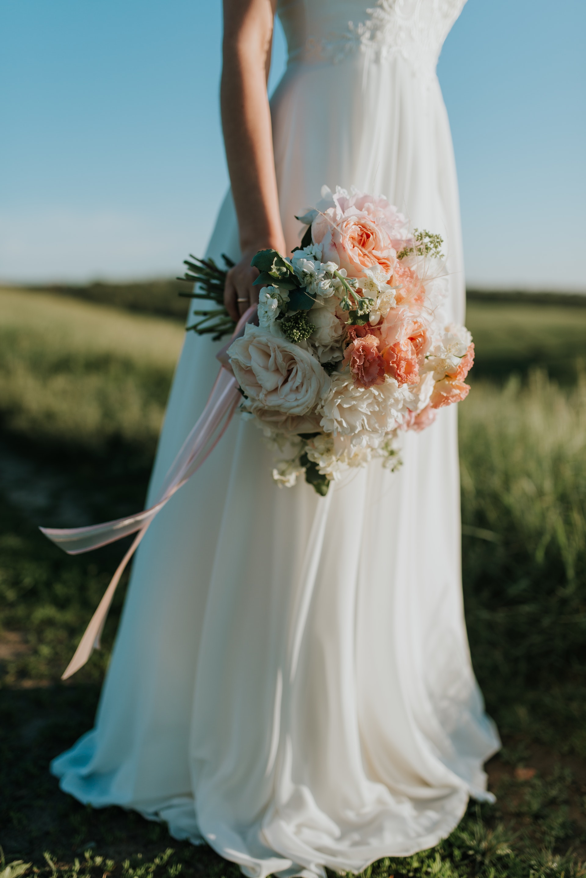 A woman wearing a white wedding dress is pictured holding a flower bouquet. | Source: Pexels