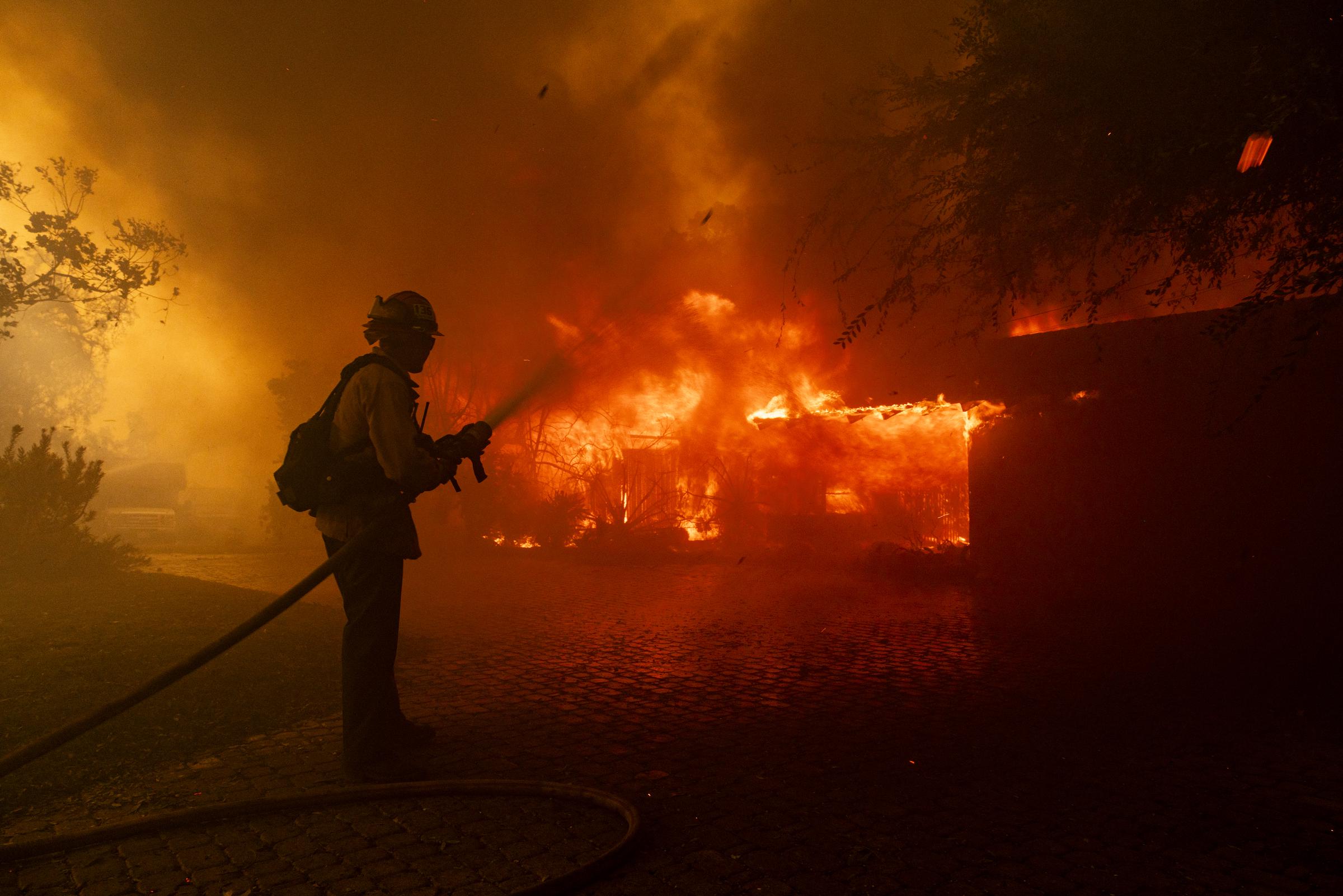 A firefighter attempting to put out a house on fire. | Source: Getty Images