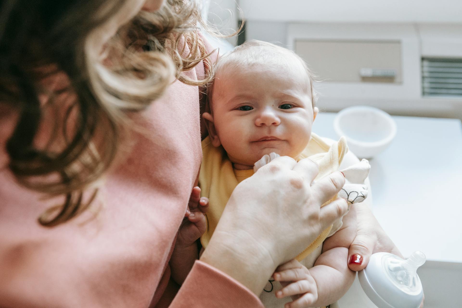 A woman holding a baby and a feeding bottle | Source: Pexels