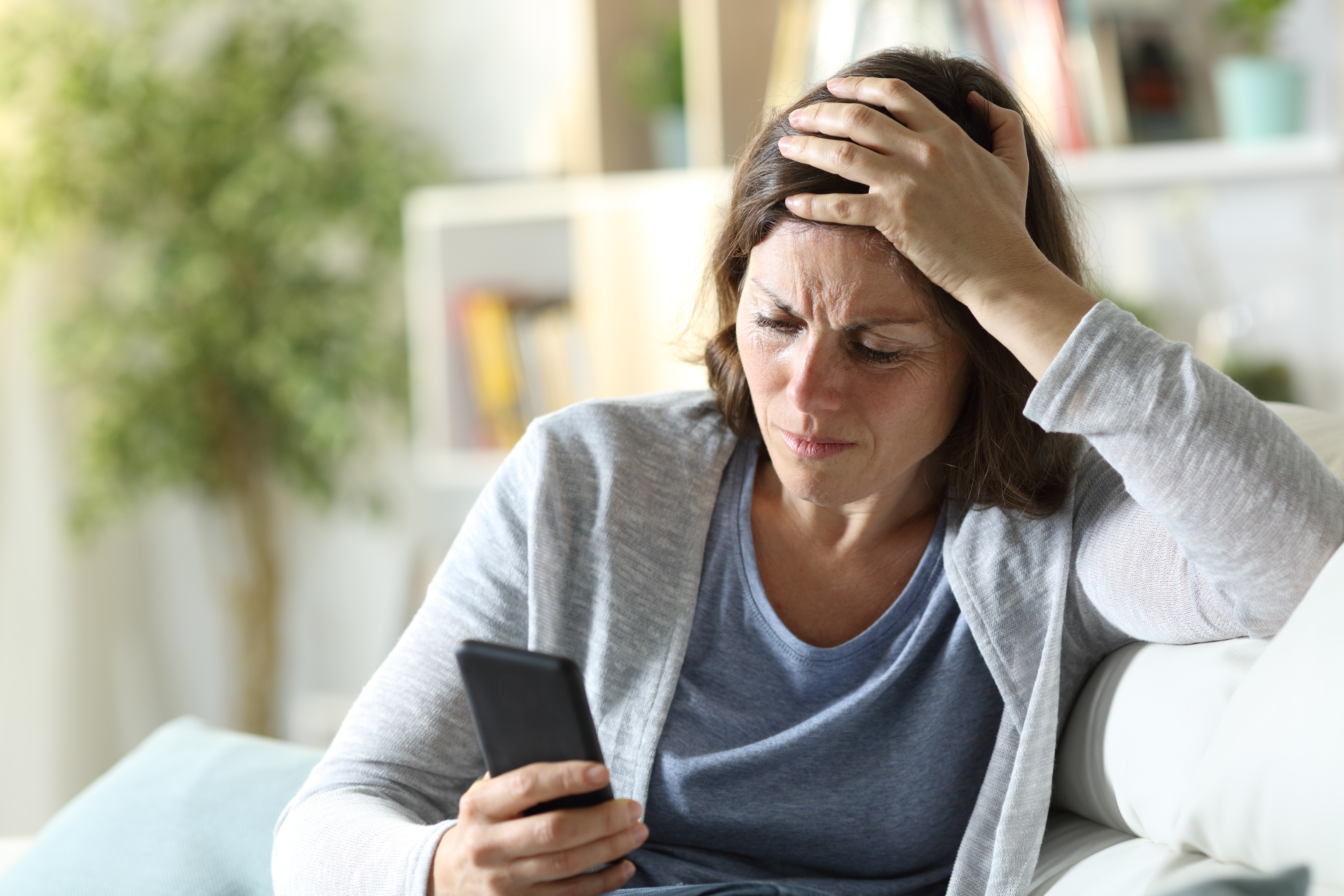 A woman looking confused and sad as she looks at her phone | Source: Shutterstock