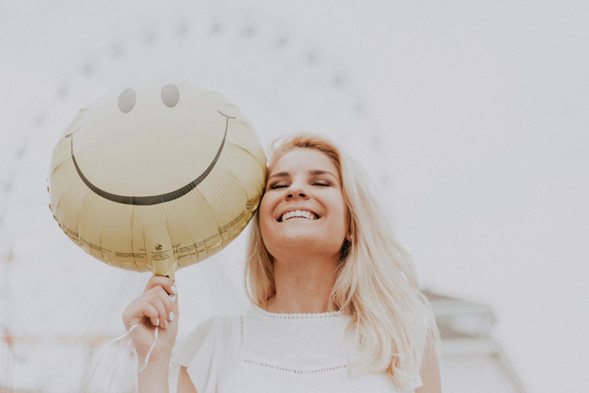 Mujer sosteniendo un globo con una sonrisa |  Fuente: Pexels