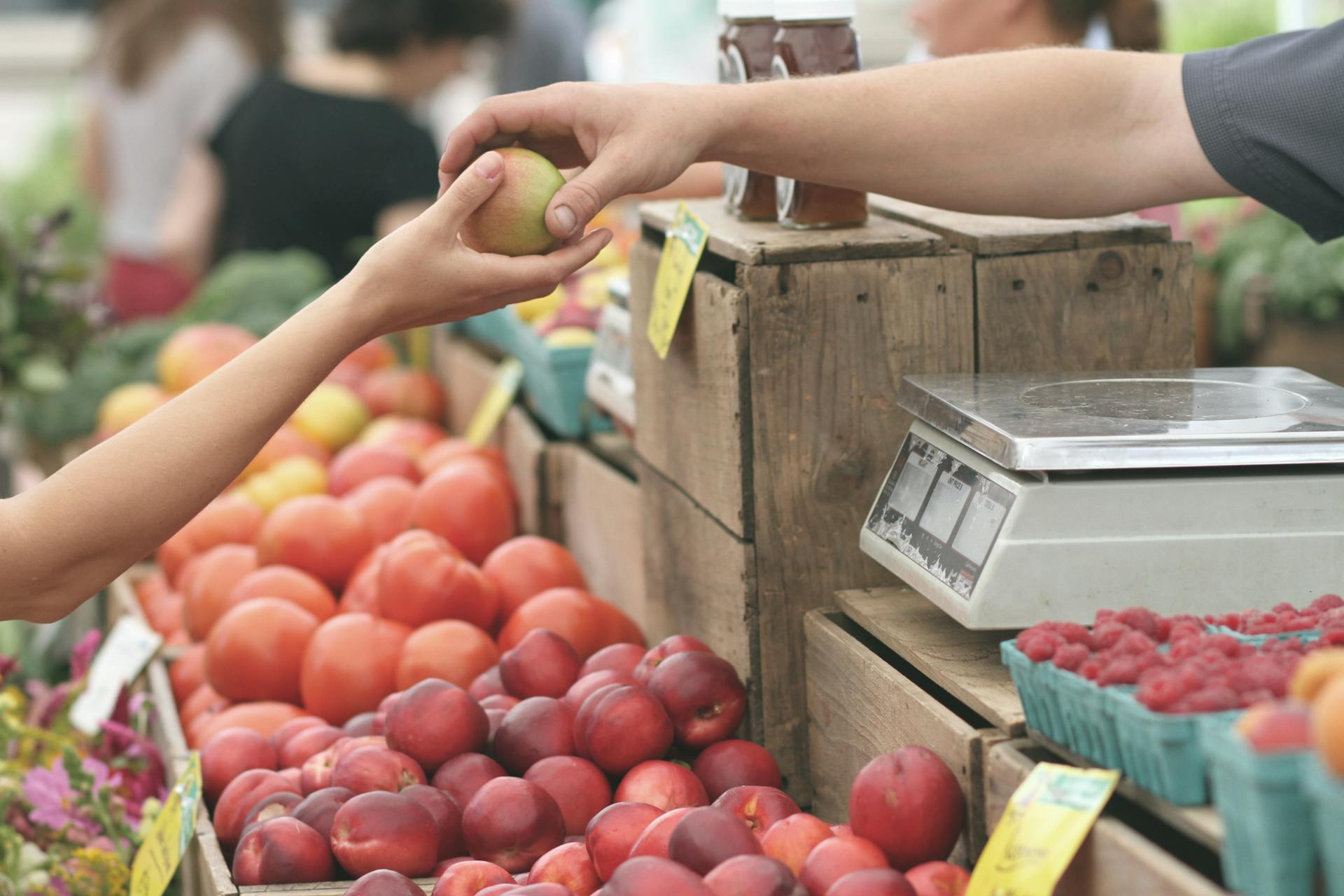 Um close-up de uma pessoa entregando uma fruta para outra pessoa | Fonte: Pexels