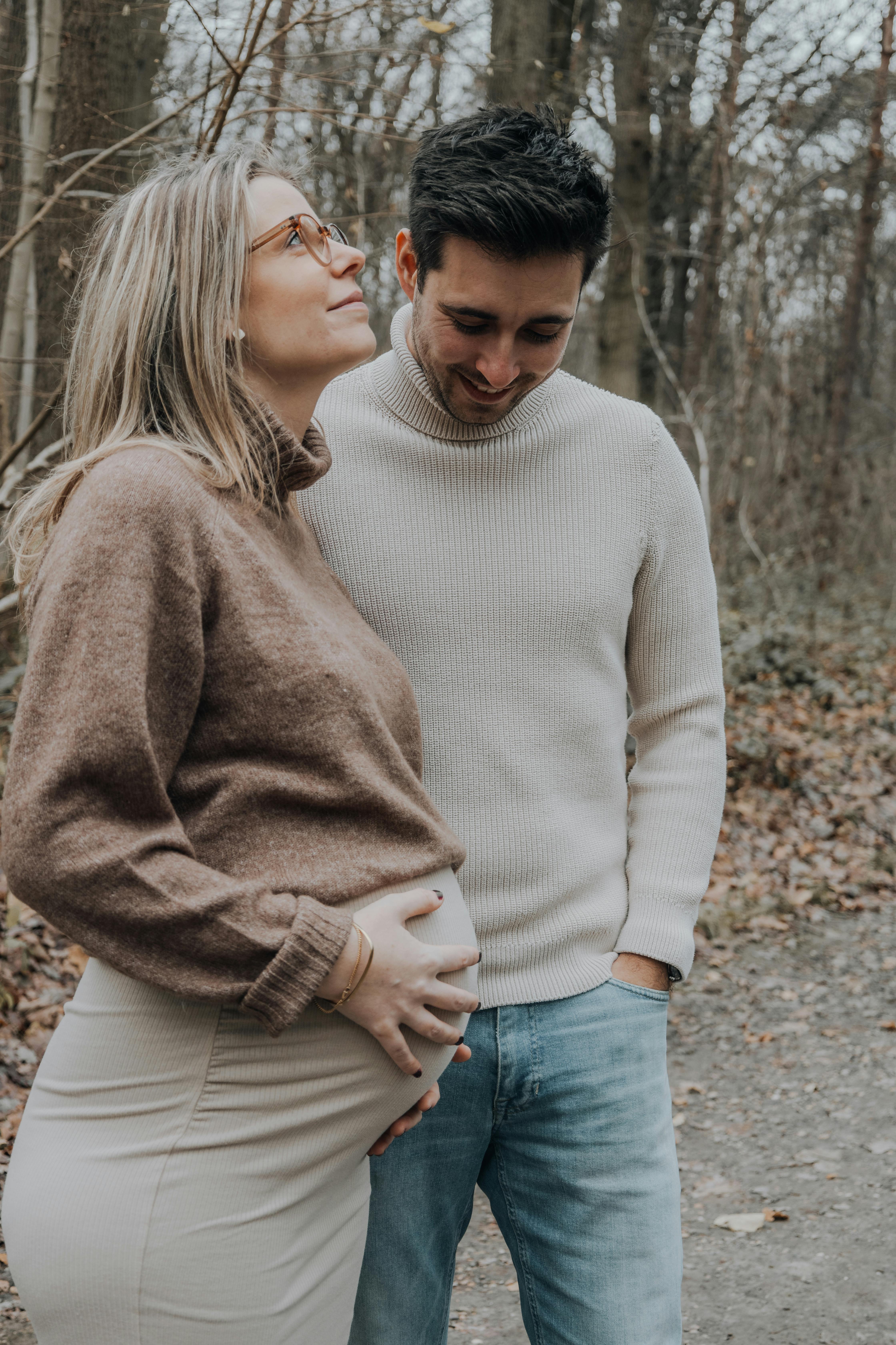 A pregnant woman cradling her baby bump while the man looks on | Source: Pexels