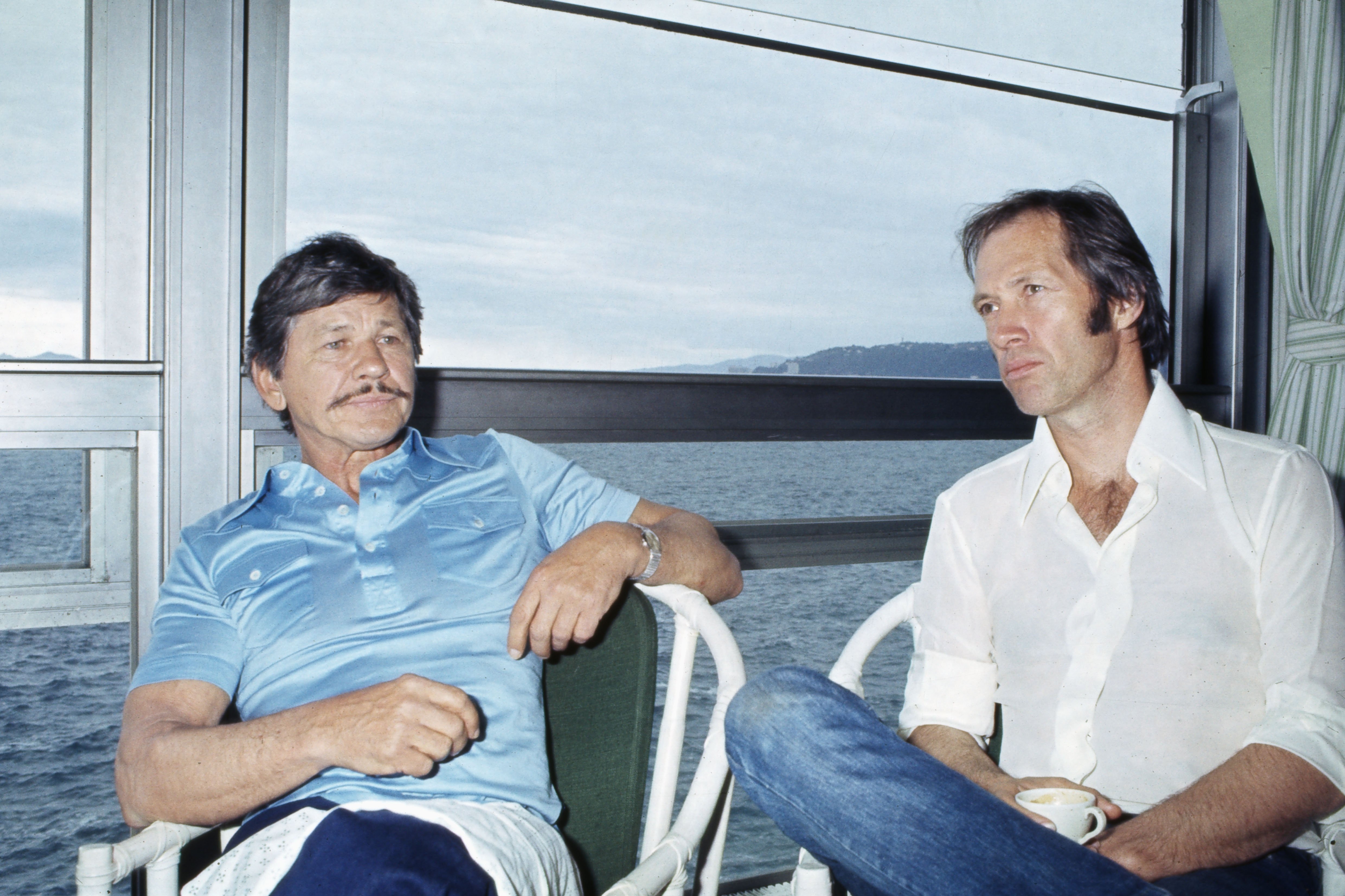 American actors Charles Bronson and David Carradine relaxing at the Cannes Film Festival, 1977. | Source: Getty Images