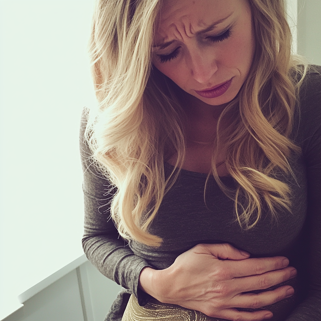 A woman clutching her stomach in pain | Source: Midjourney