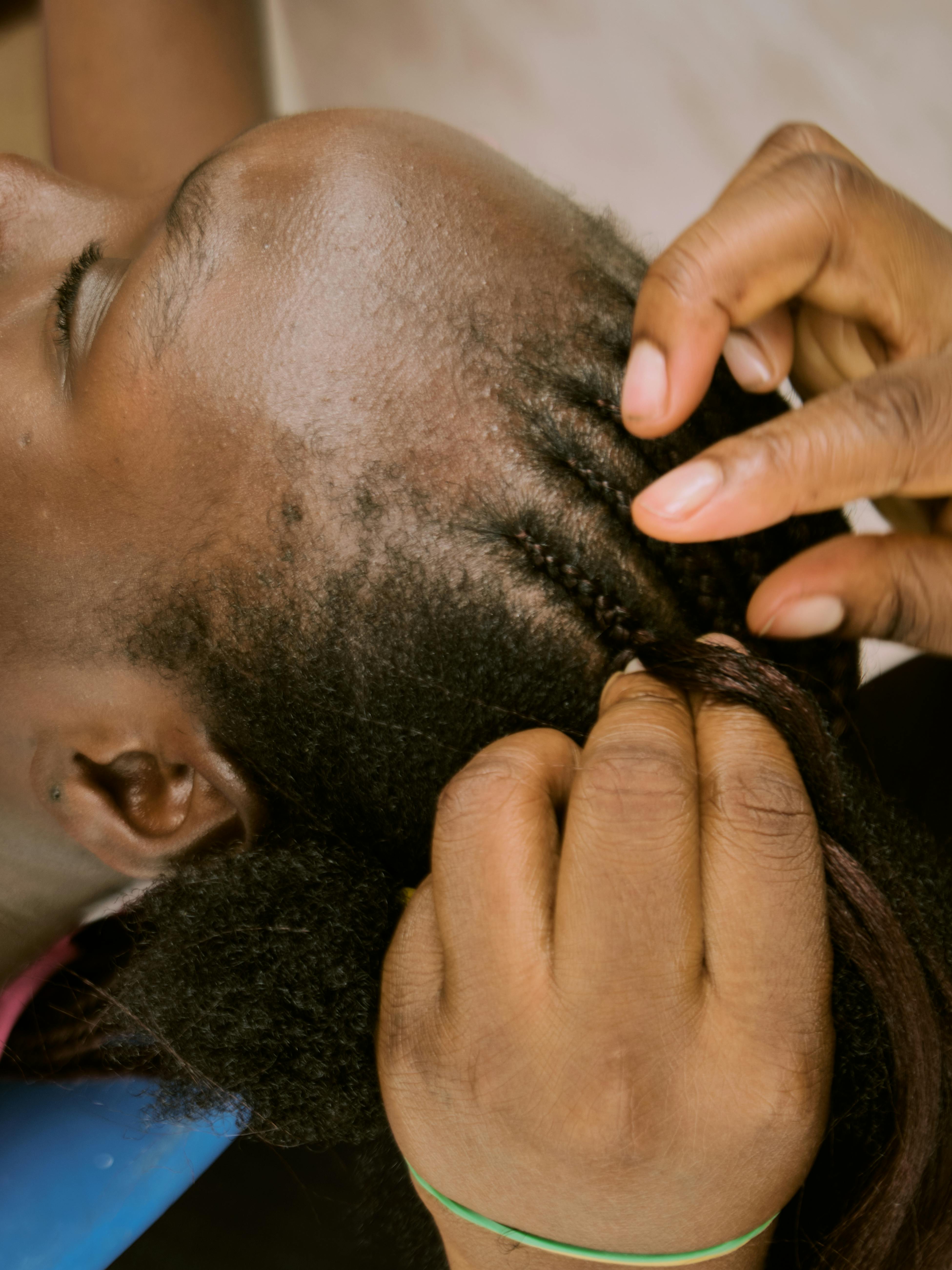 For illustration purposes only. A woman's hair being braided with hair extensions | Source: Pexels