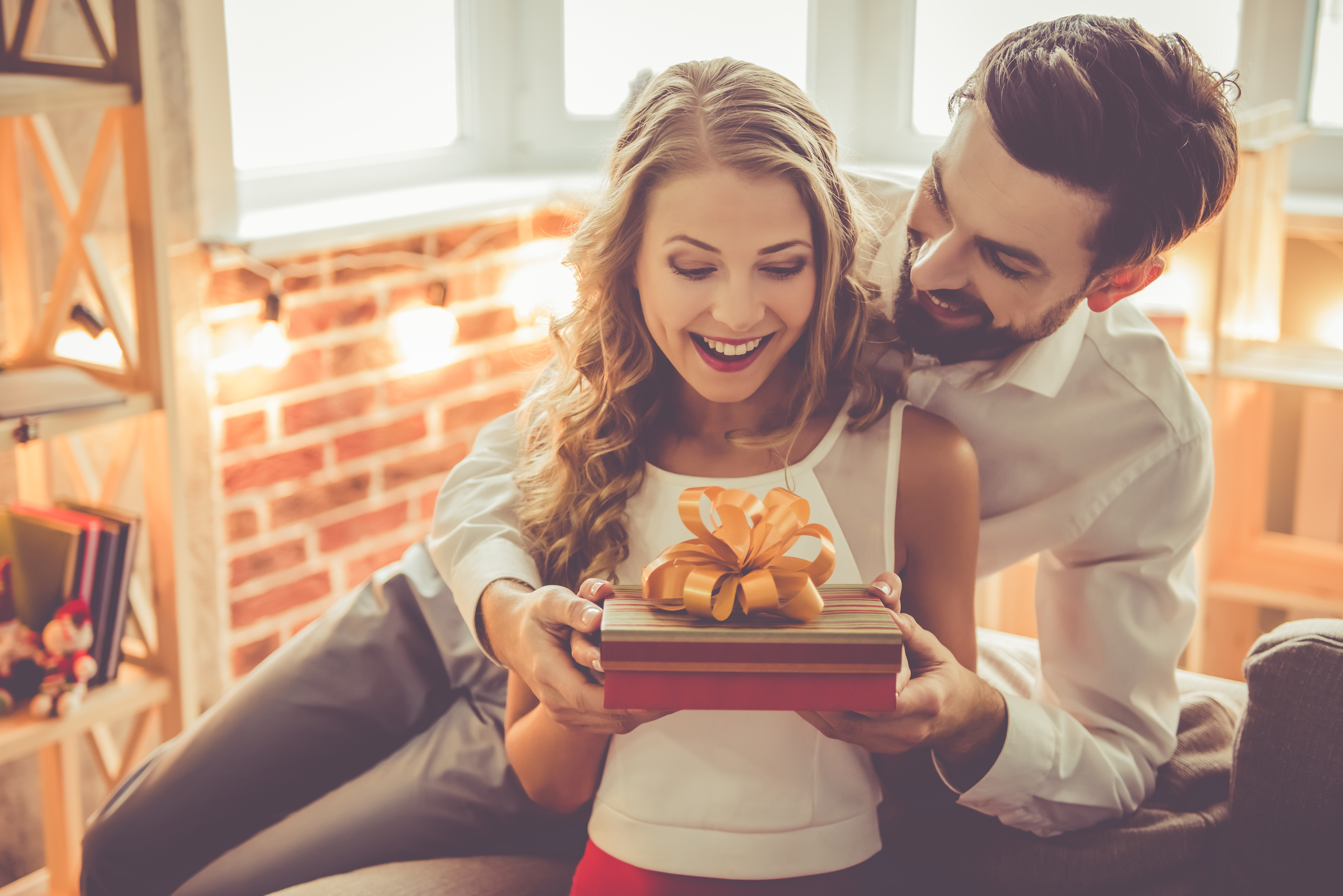 A young man giving his girlfriend a gift box | Source: Shutterstock