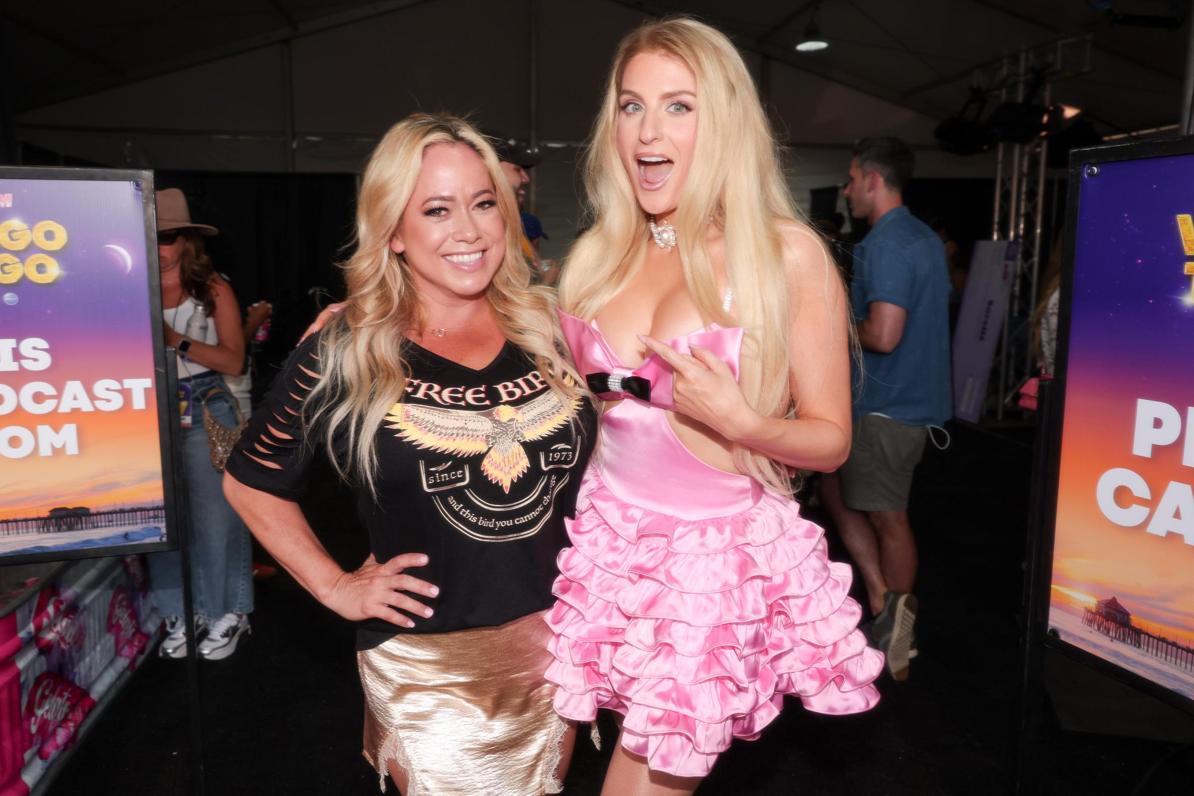 Backstage at iHeartRadio's Wango Tango, Meghan Trainor poses with Sabrina Bryan, flashing a surprised expression beside a themed display.