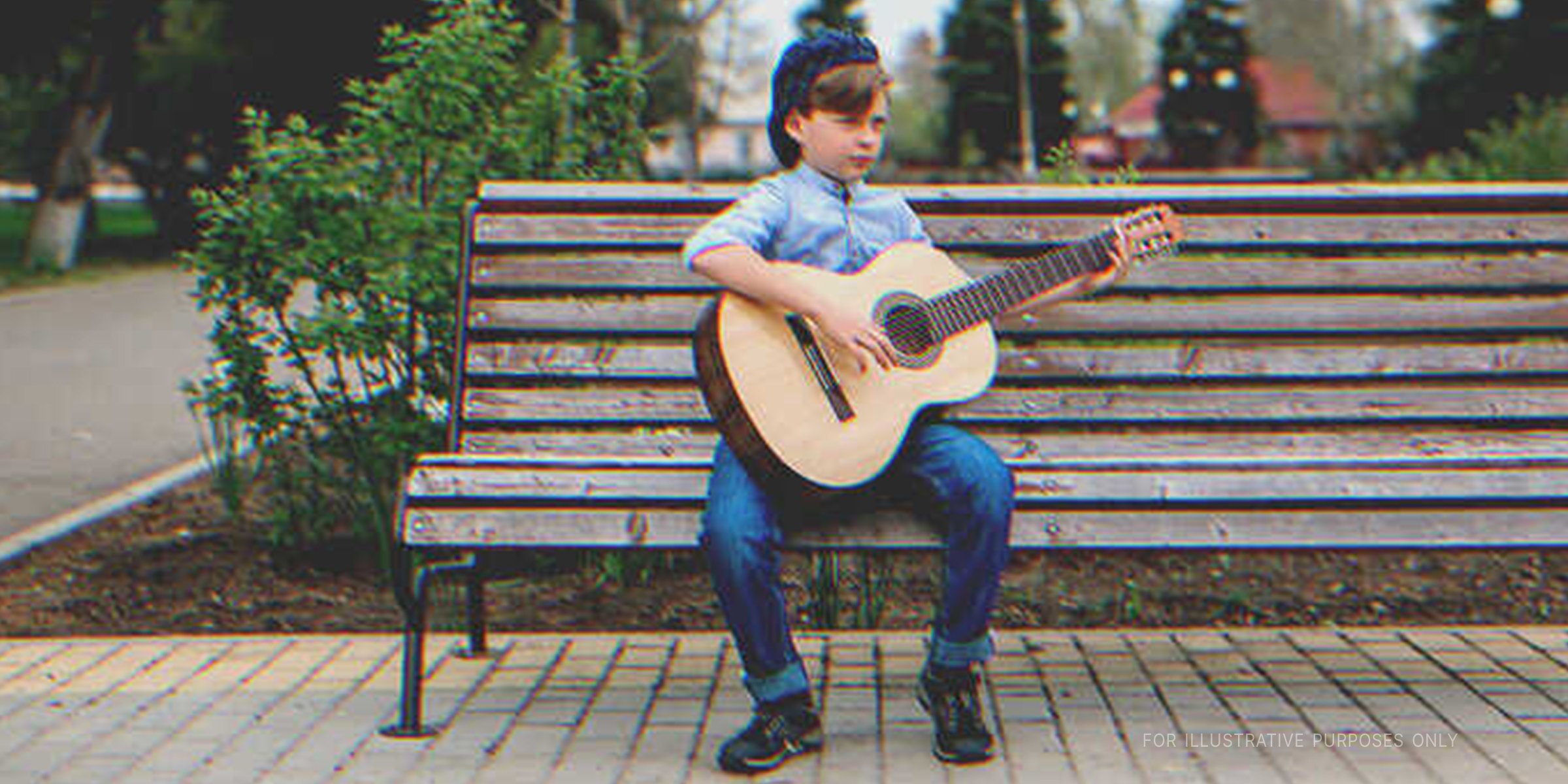 Boy playing guitar on a bench. | Getty Images