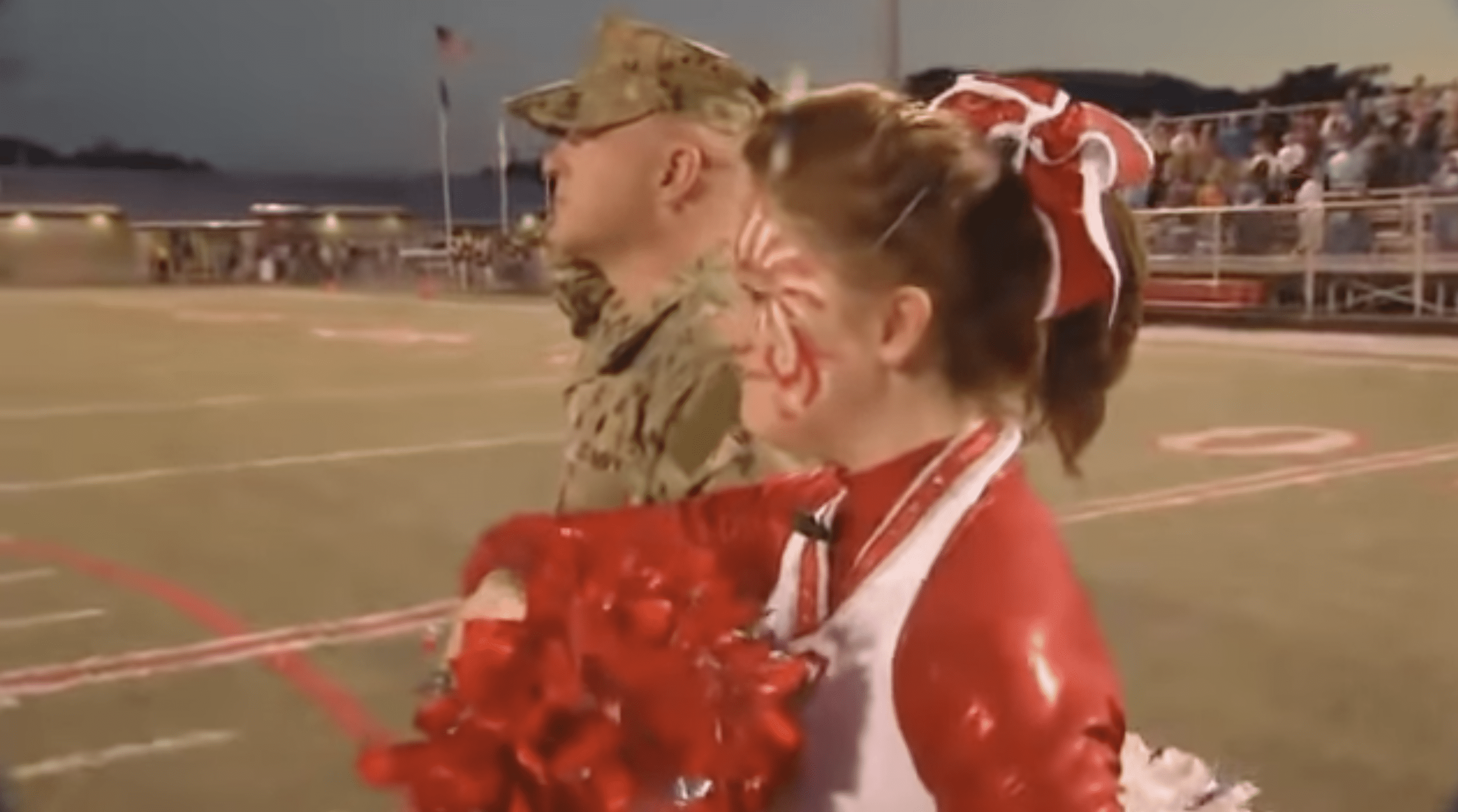 Kendall and Dale Williams standing in the field, hearing the national anthem before the game. | Photo: YouTube.com/WLOS News 13