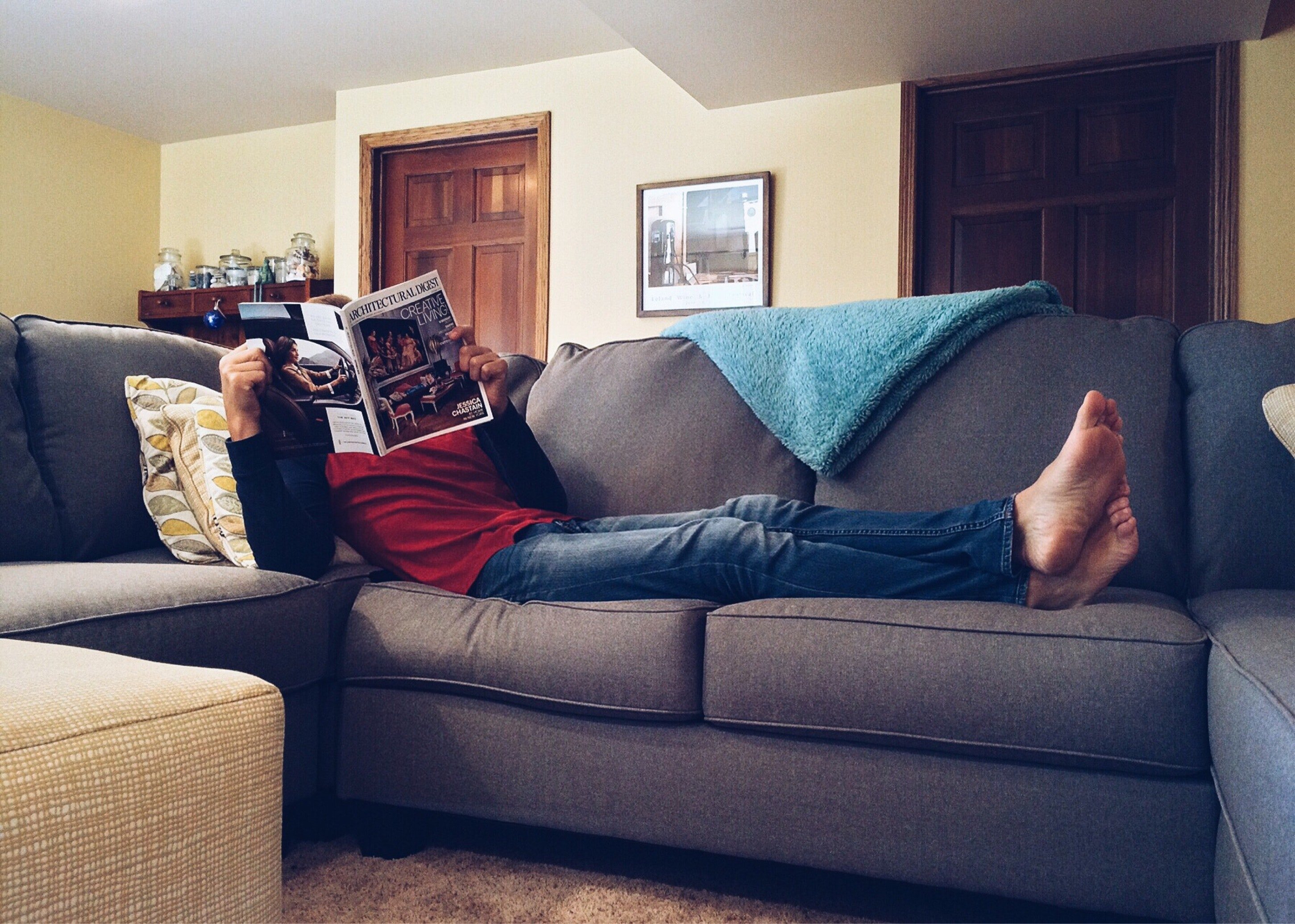 Hombre leyendo una revista acostado en un sofá. | Foto: Pexels