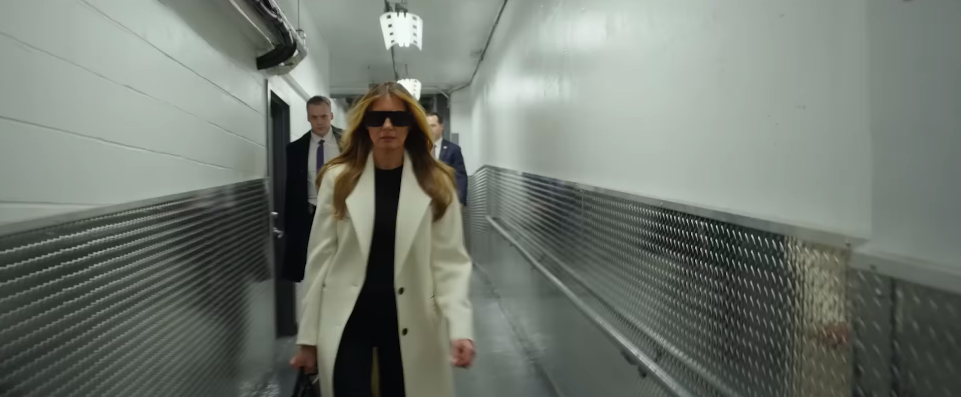 Melania Trump walking along a corridor with agents/secret service men behind her. | Source: YouTube/Amazon MGM Studios