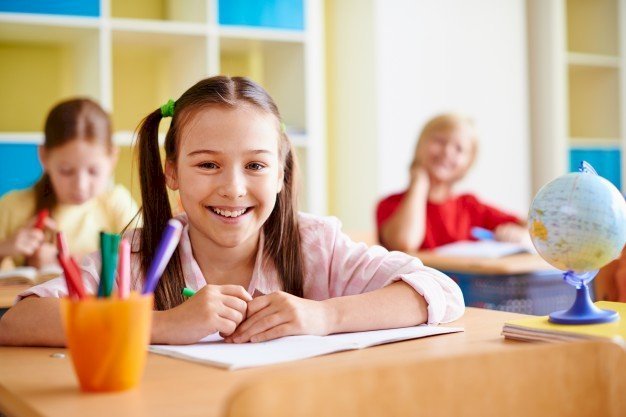 A girl smiling in a classroom | Source: Freepik
