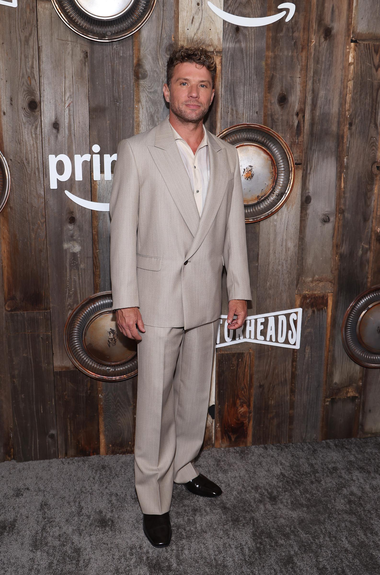 Ryan Phillippe looks composed as he poses solo in front of the "Motorheads" step-and-repeat during the screening at the Academy Museum, wearing a tailored light suit and relaxed expression under soft evening lighting.