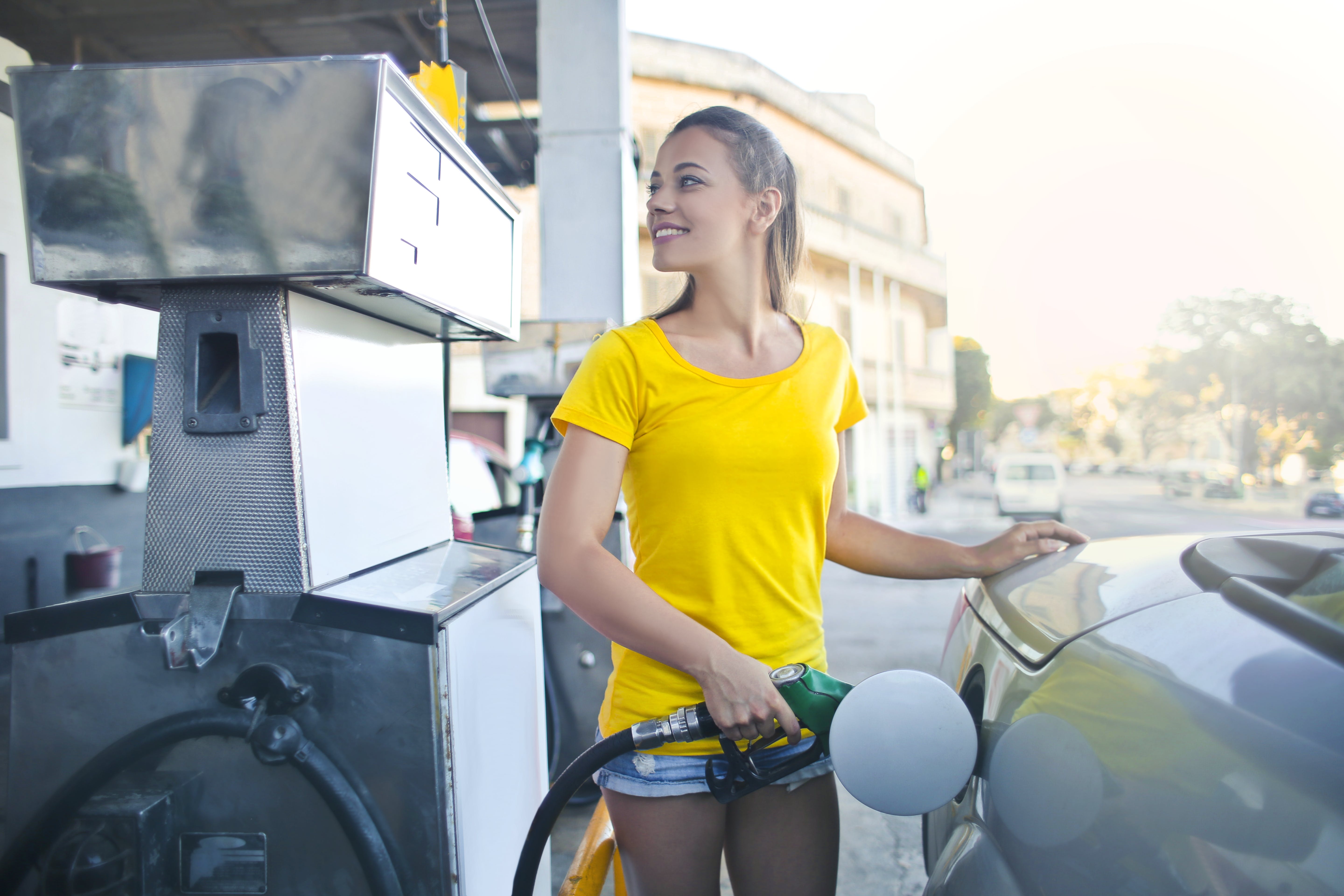 A woman in a yellow top fueling her car. | Source: Pexels