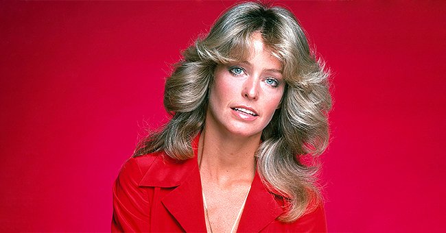 Farrah Fawcett poses for a photo before a red backdrop, circa 1976. | Source: Getty Images