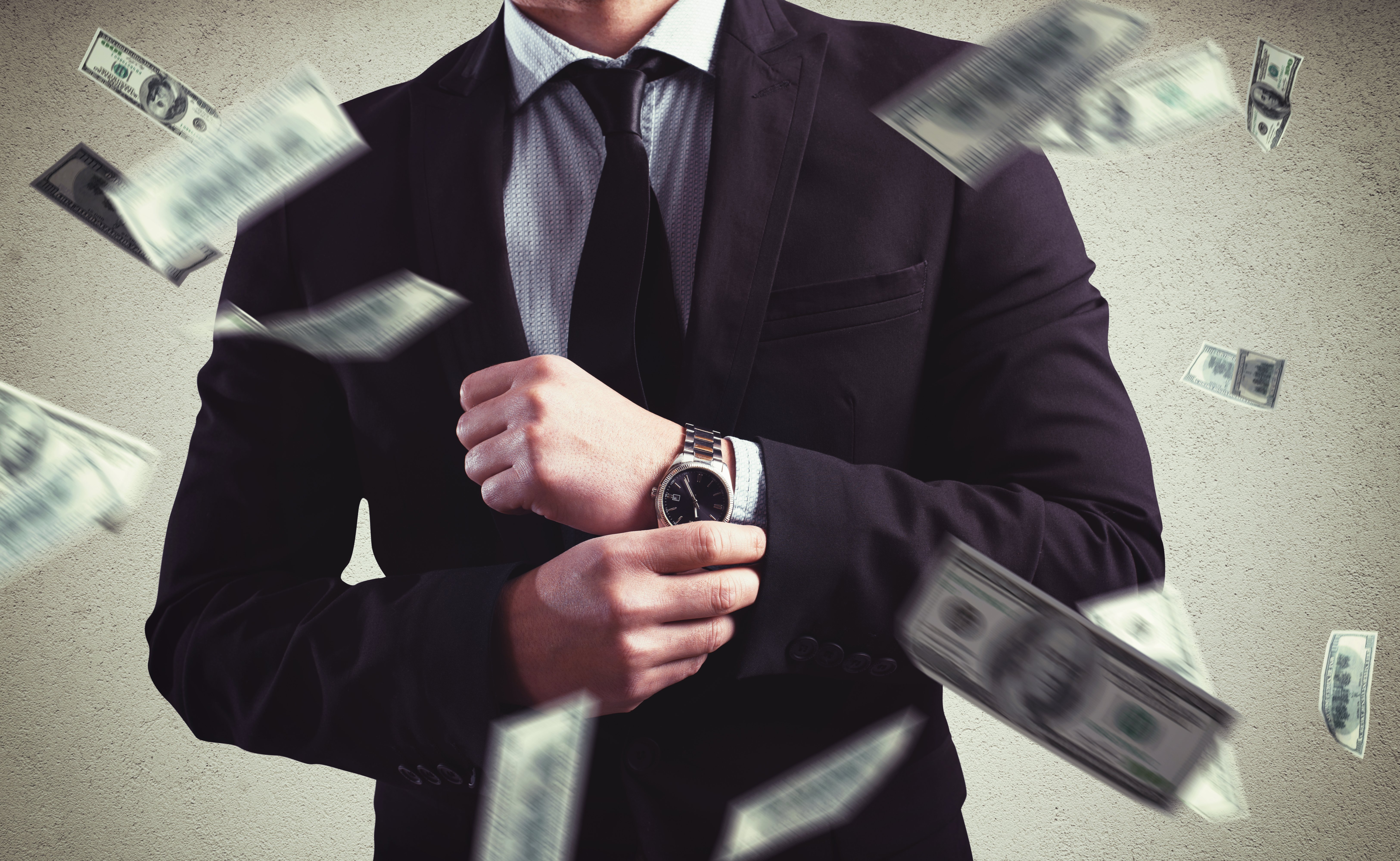Dollar bills flying around a man who is corporately dressed | Photo: Shutterstock