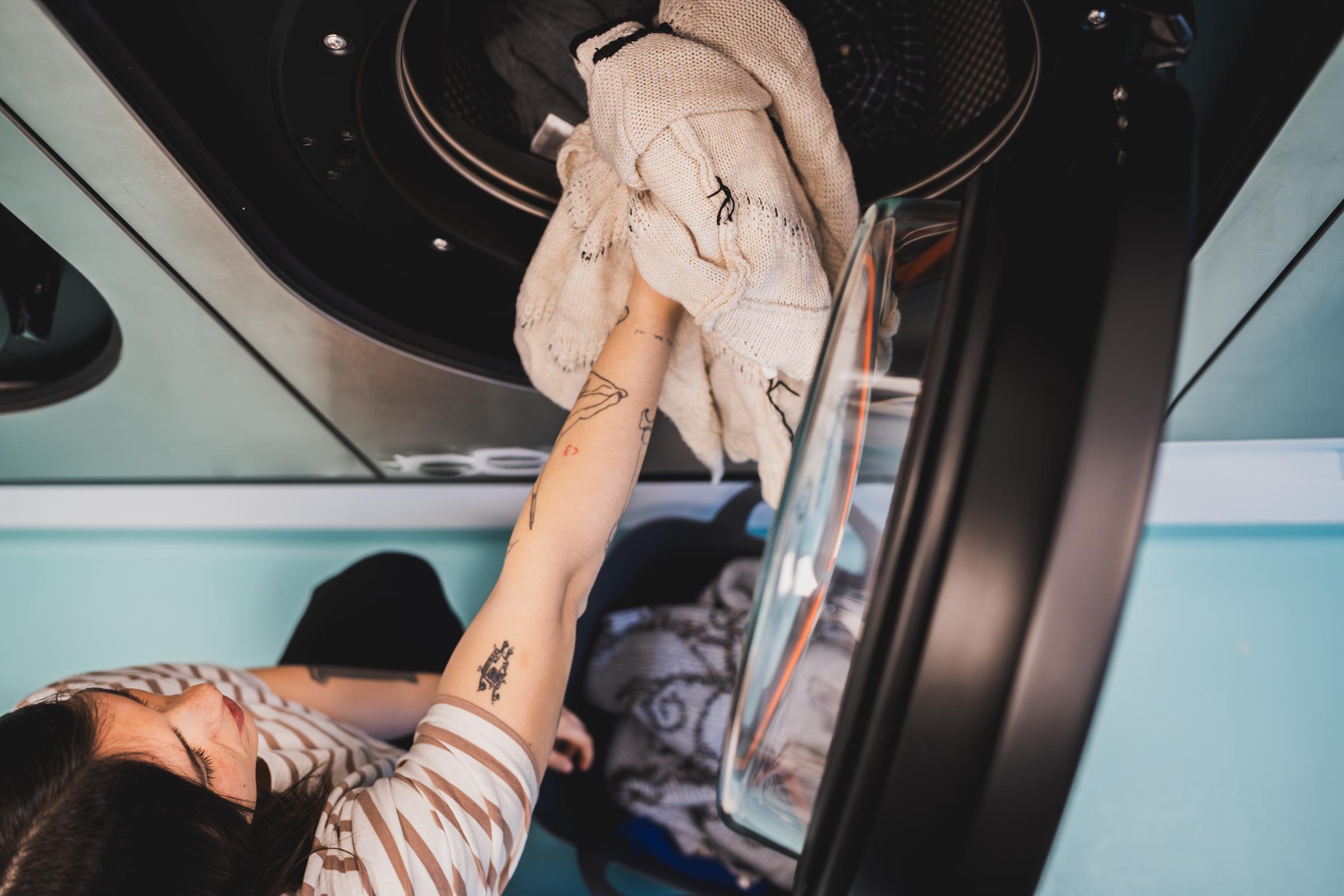 A young woman taking out her sweater from the washing machine | Source: Getty Images