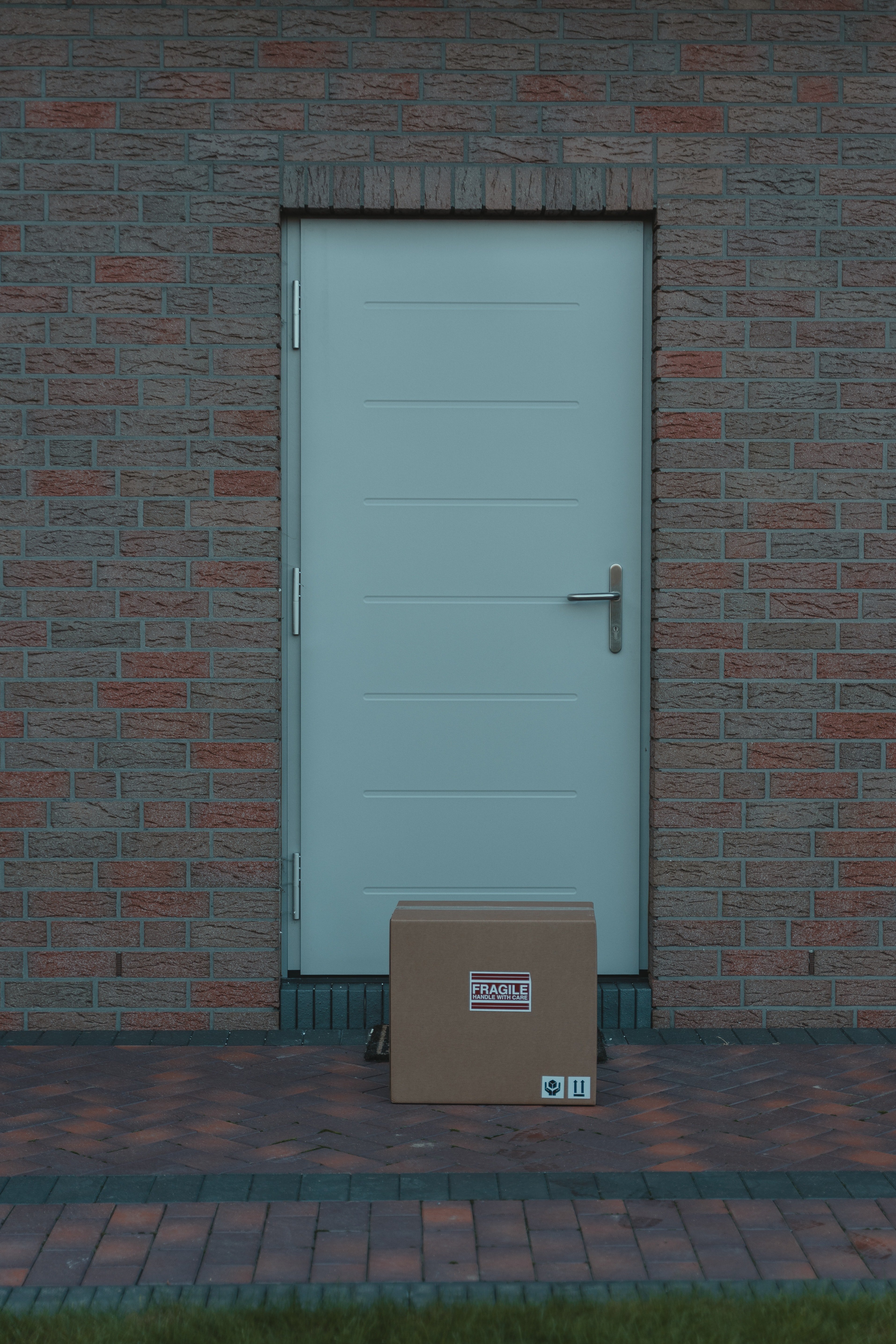 Brown cardboard box beside white wooden door. | Source: Pexels