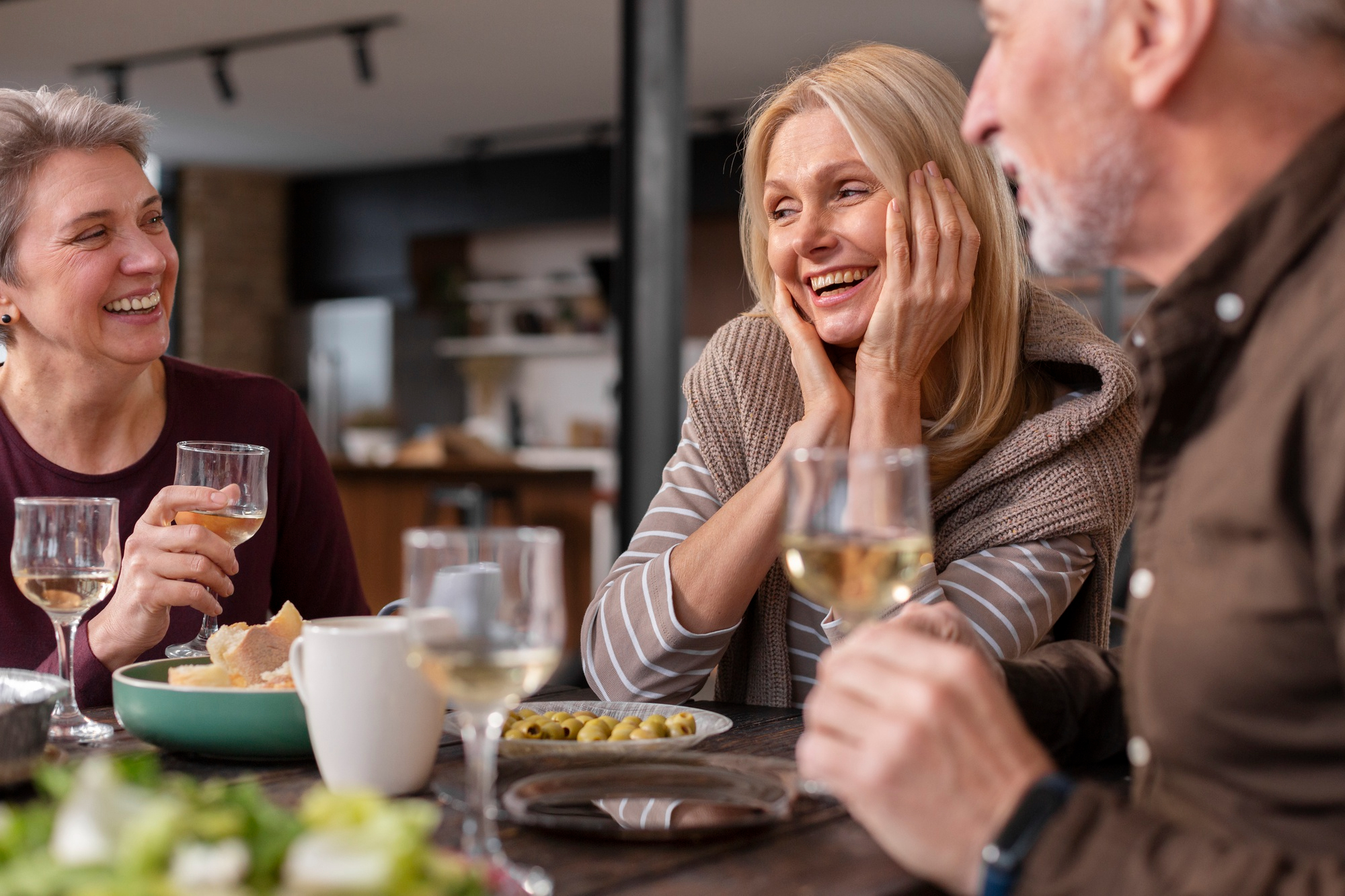 A happy couple and woman having a toast while enjoying a meal | Source: Freepik