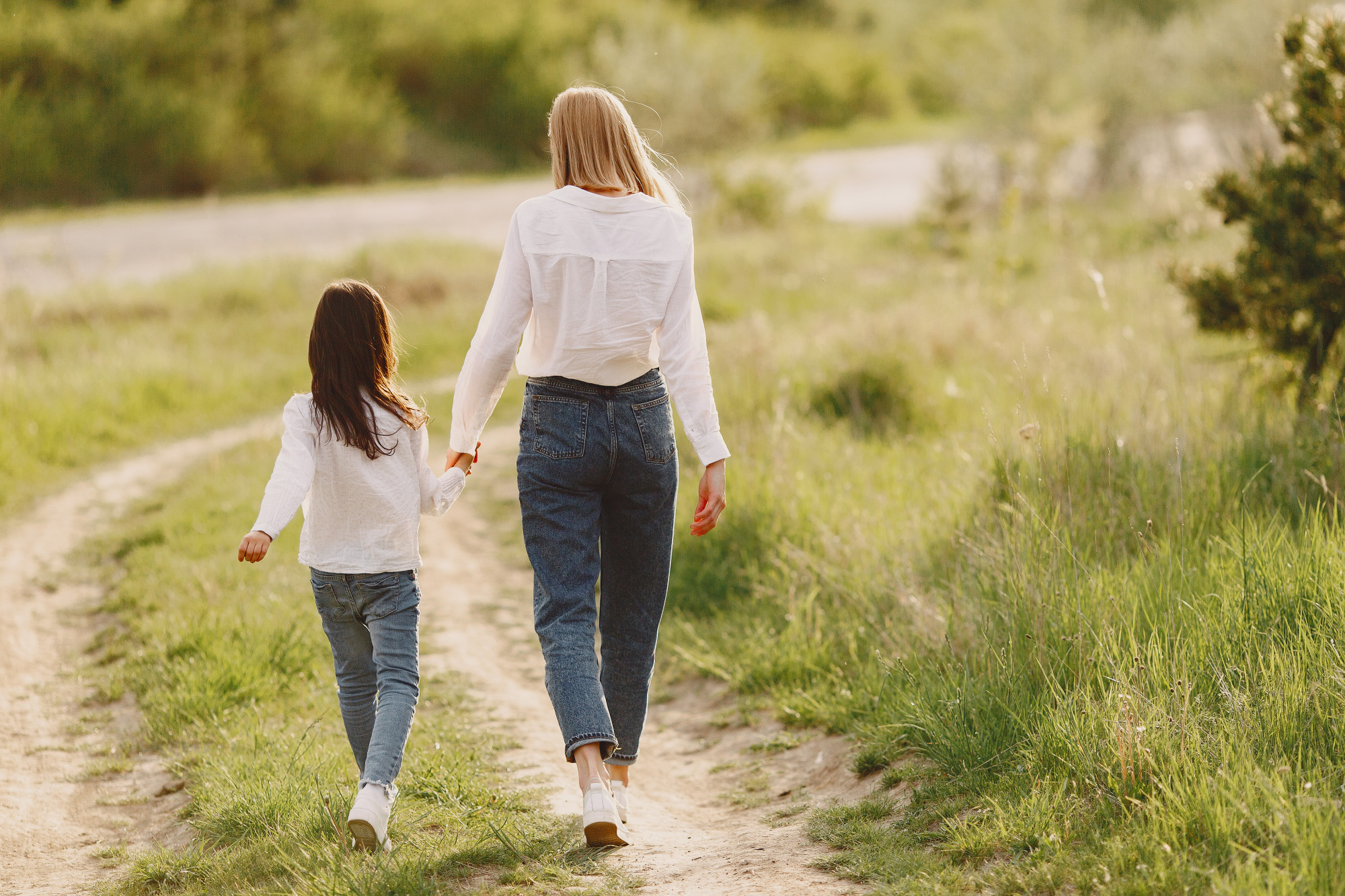 A woman and a child holding hands while walking away | Source: Pexels