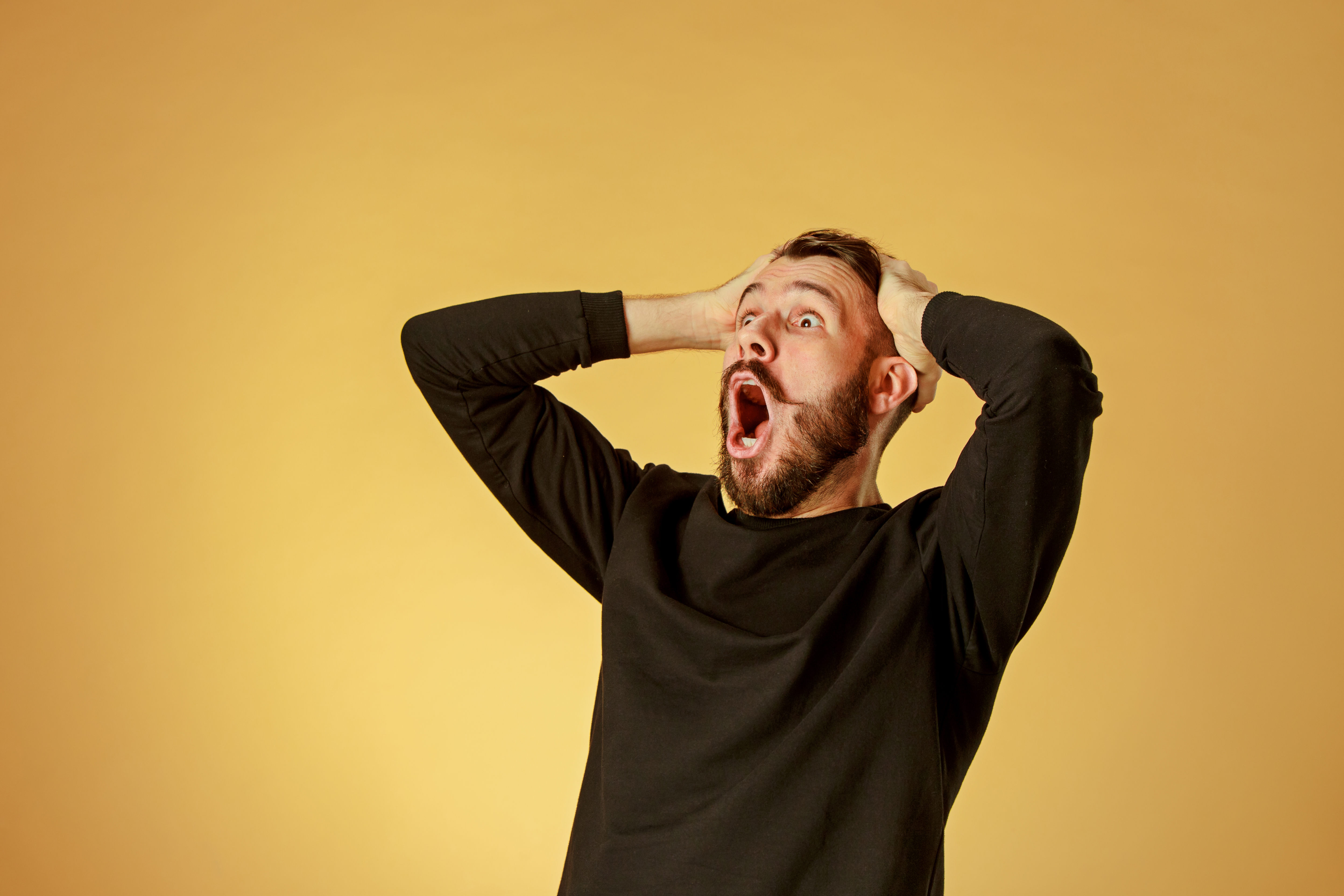 A shocked young man holding his head | Source: Shutterstock