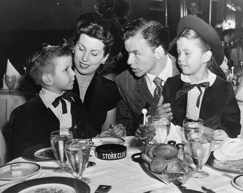 Frank Sinatra, sa femme et ses enfants, Nancy et Frankie, Jr, dînant dans la salle des louveteaux du Stork Club de Sherman Billingsley, dissipant ainsi toute rumeur de rupture avec sa femme. Le 17 octobre 1947. | Photo : Getty Images