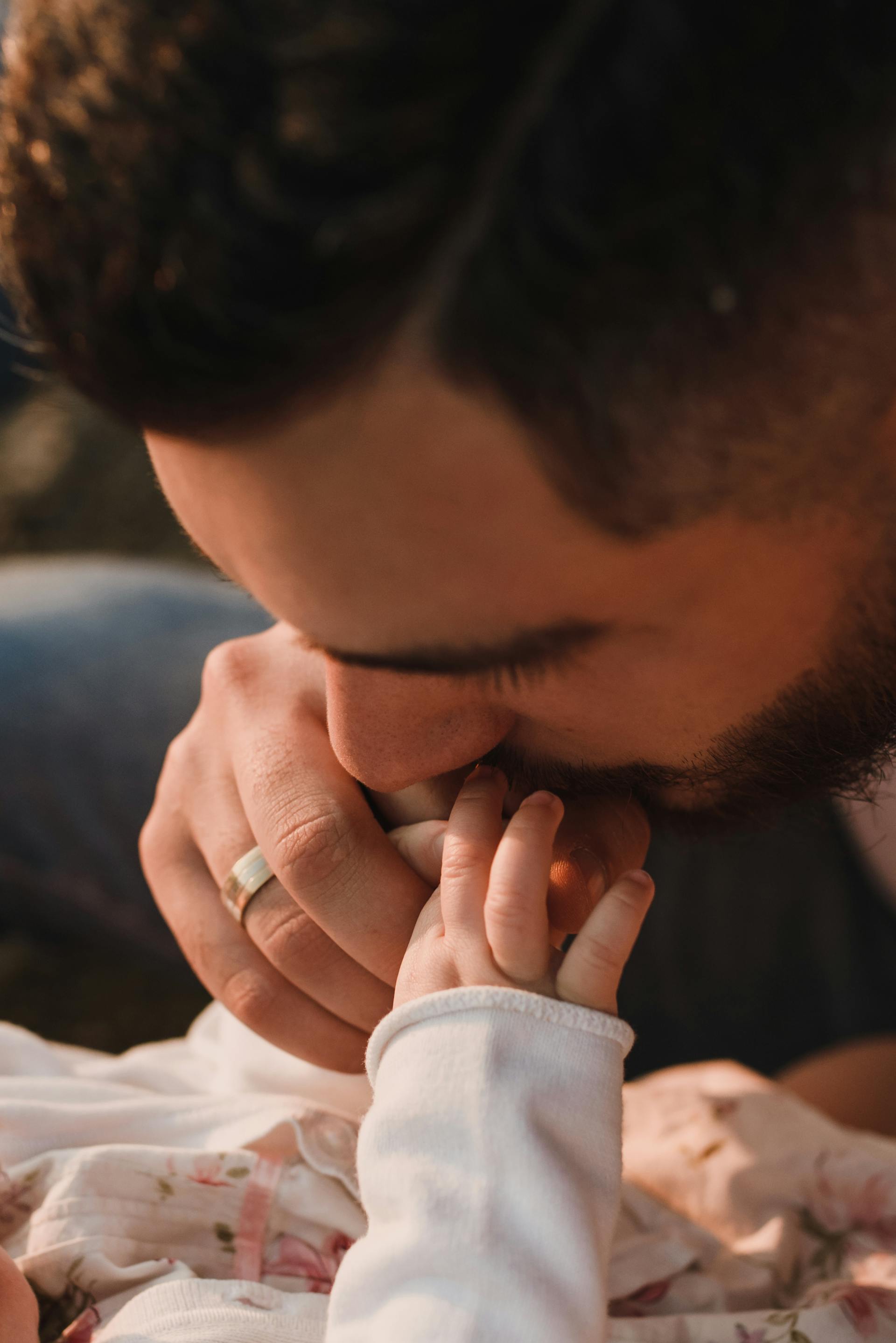 A man kissing a baby's hand | Source: Pexels