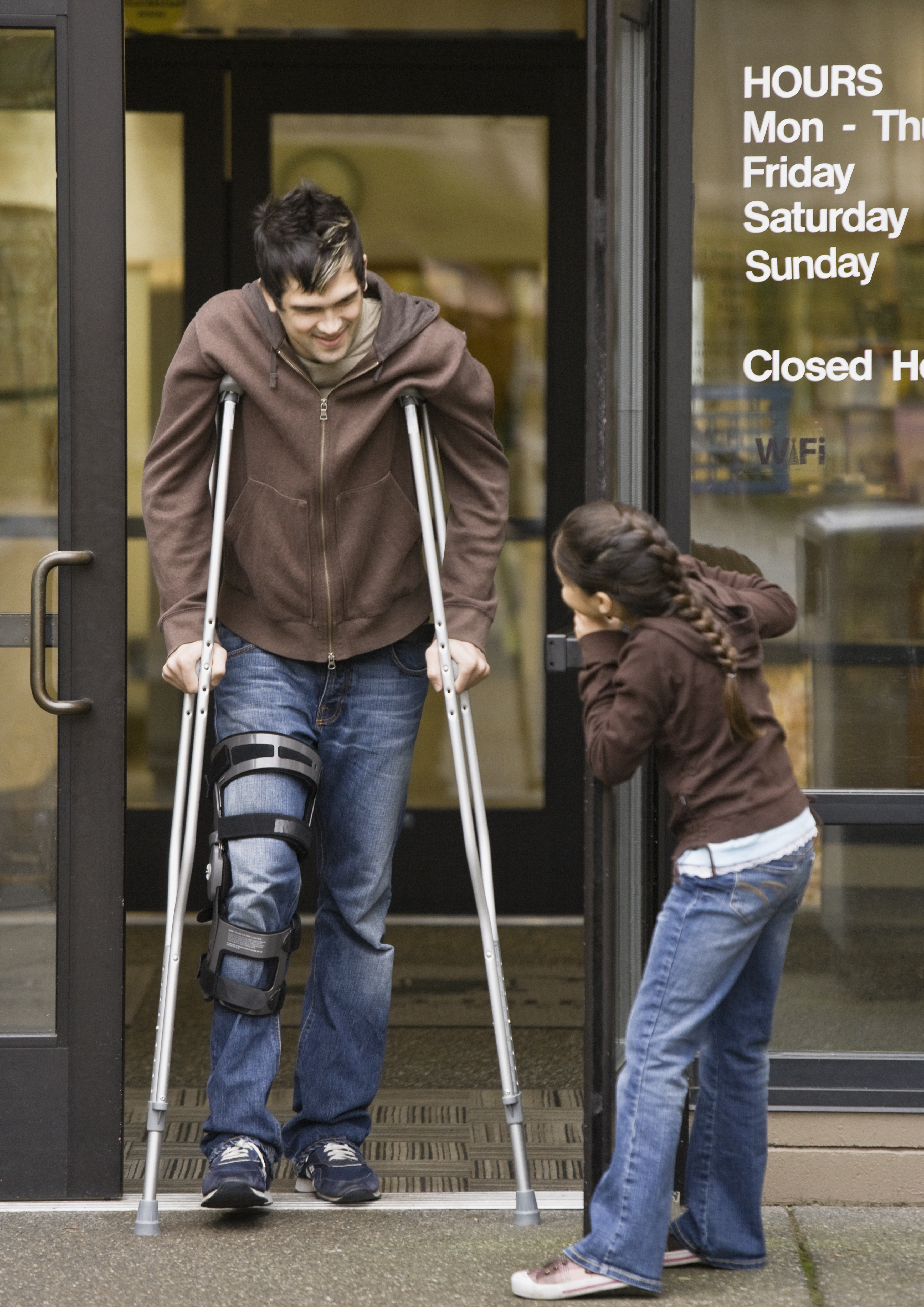 A little girl holding the door for a man on crutches. | Source: Getty Images