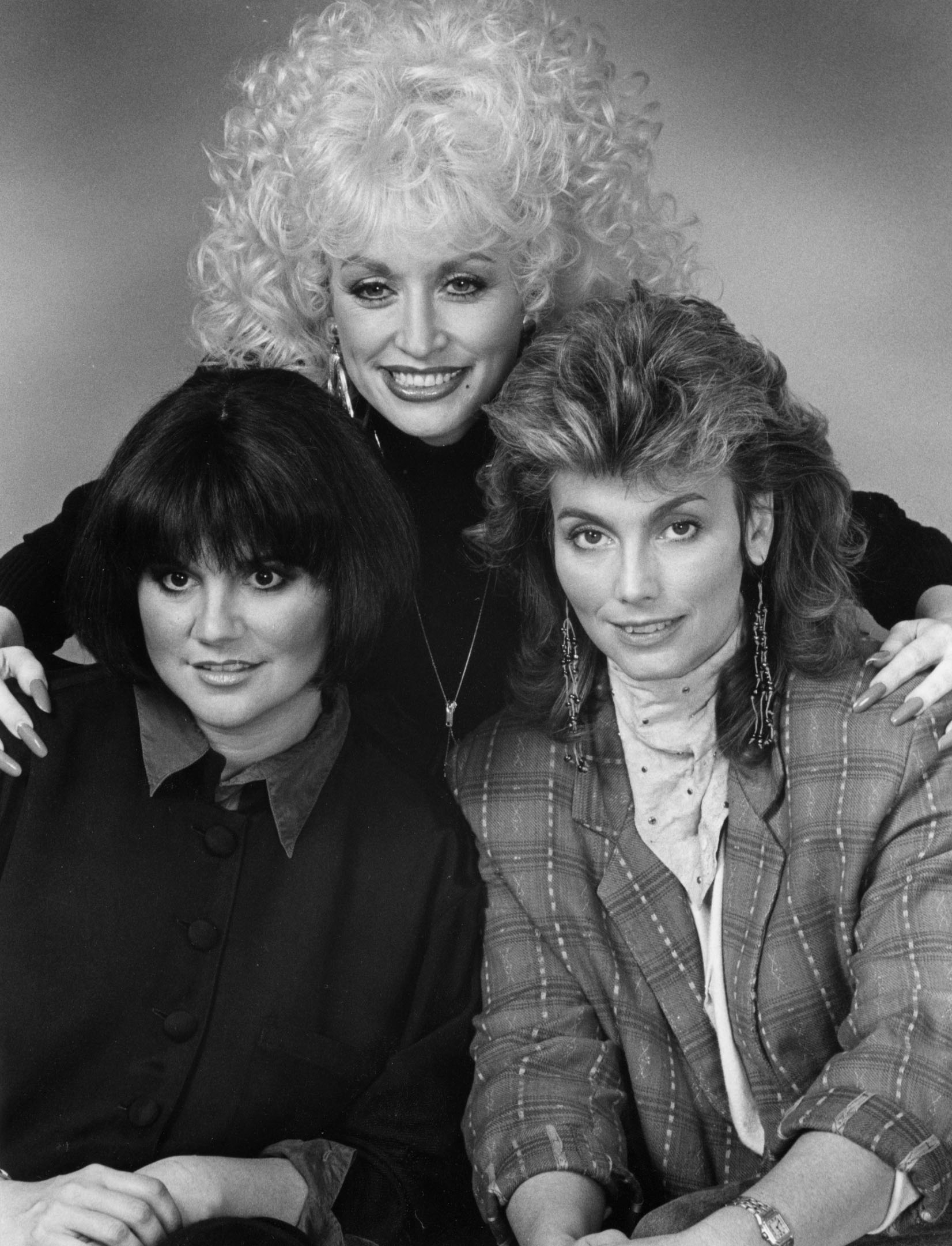Singers Linda Ronstadt, Dolly Parton, and Emmylou Harris pose for a photo session at a Universal City hotel on March 13,1987 in Hollywood, California. ┃Source: Getty Images