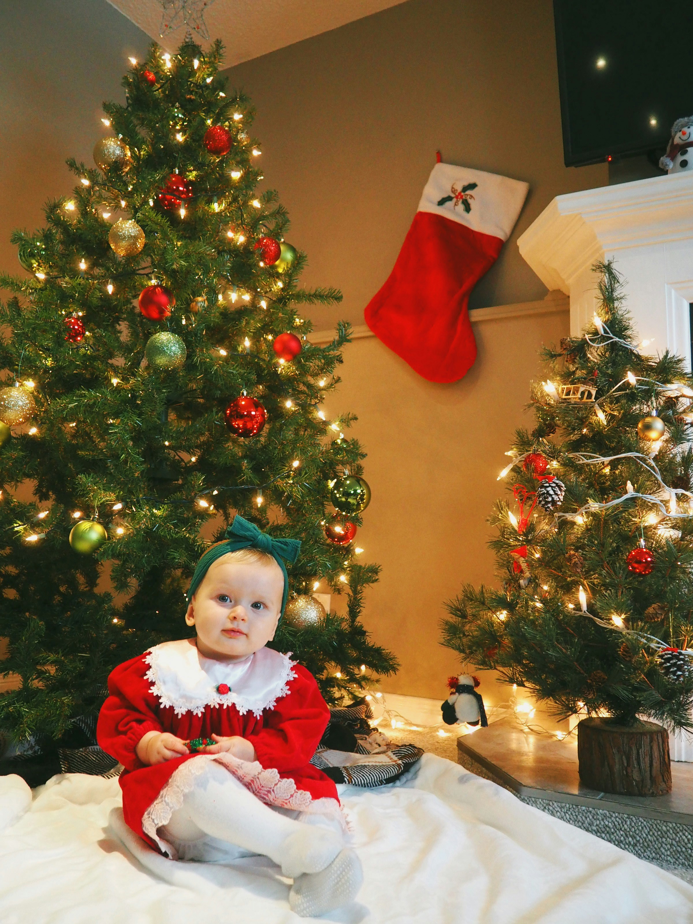 A baby girl sitting against the backdrop of Christmas decorations | Source: Unsplash