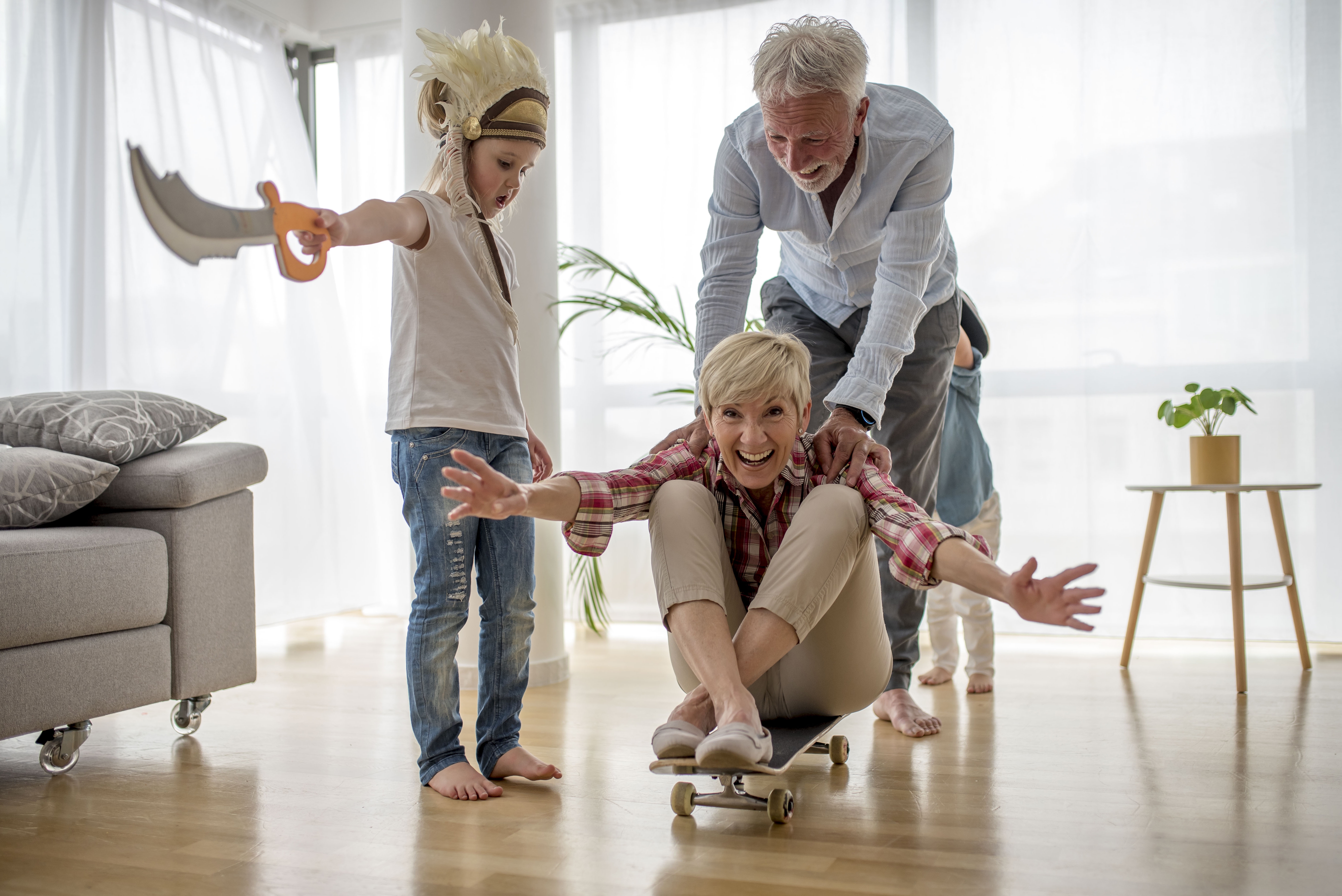 A grandmother sitting on a skateboard as her husband pushes her and her grandson watches | Source: Freepik