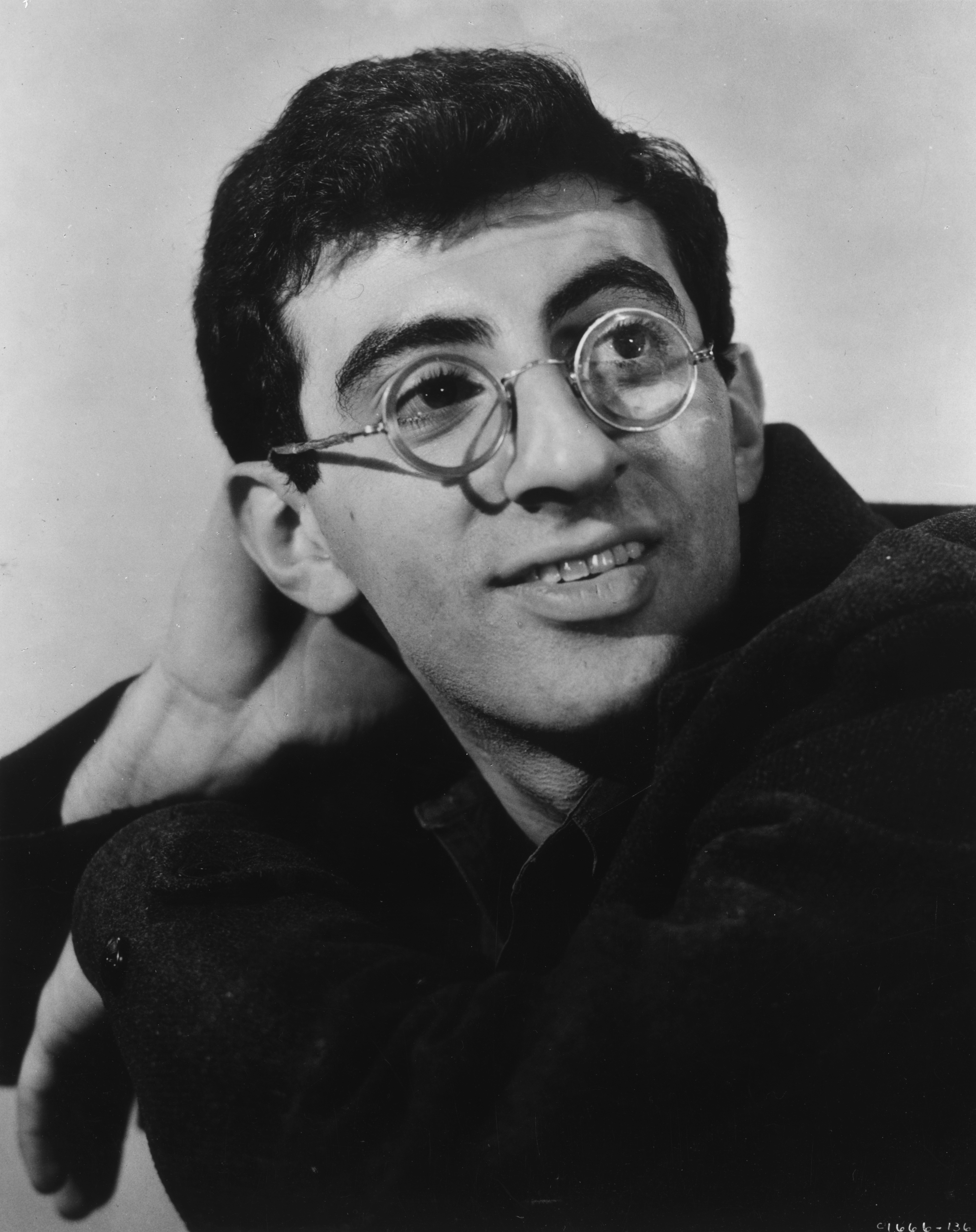 Promotional headshot portrait of Jamie Farr wearing round wire-rimmed glasses on January 1, 1955 | Source: Getty Images