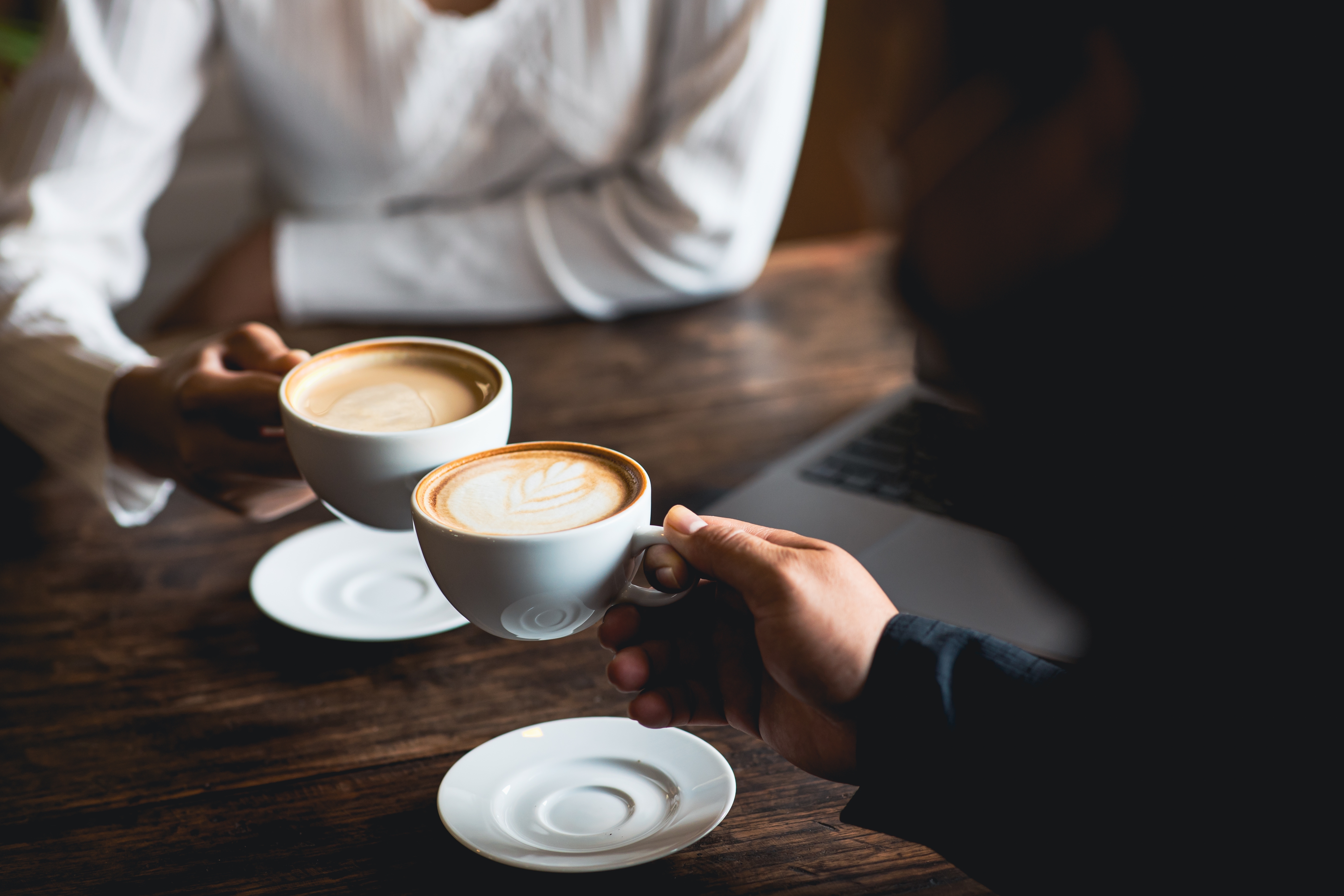 Close-up of a man and woman clinking coffee cups in a café | Source: Shutterstock
