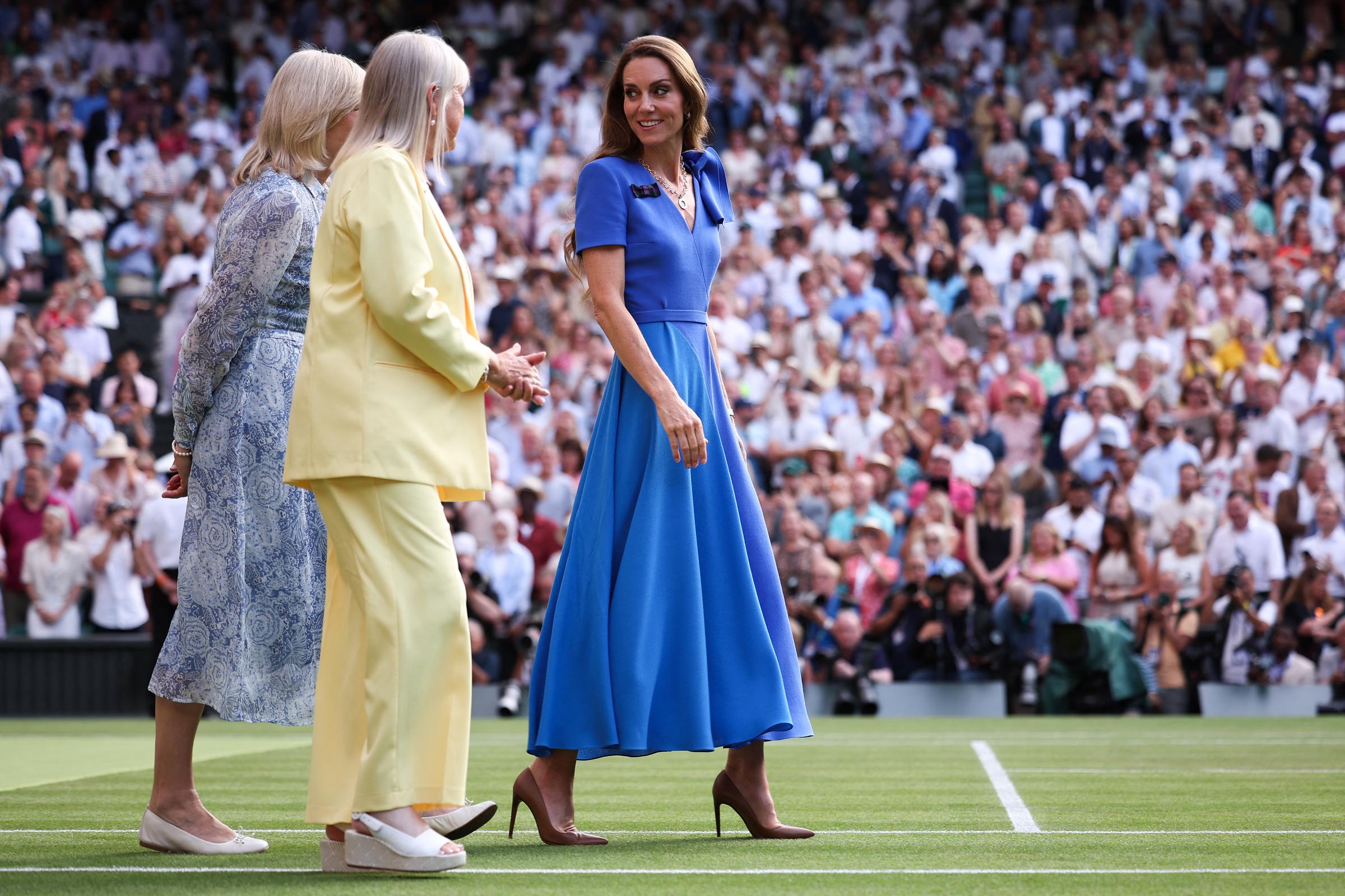 Princess Catherine walks alongside two women on the Wimbledon court ahead of the award presentation. She bears a small smile while making her way across the grass.