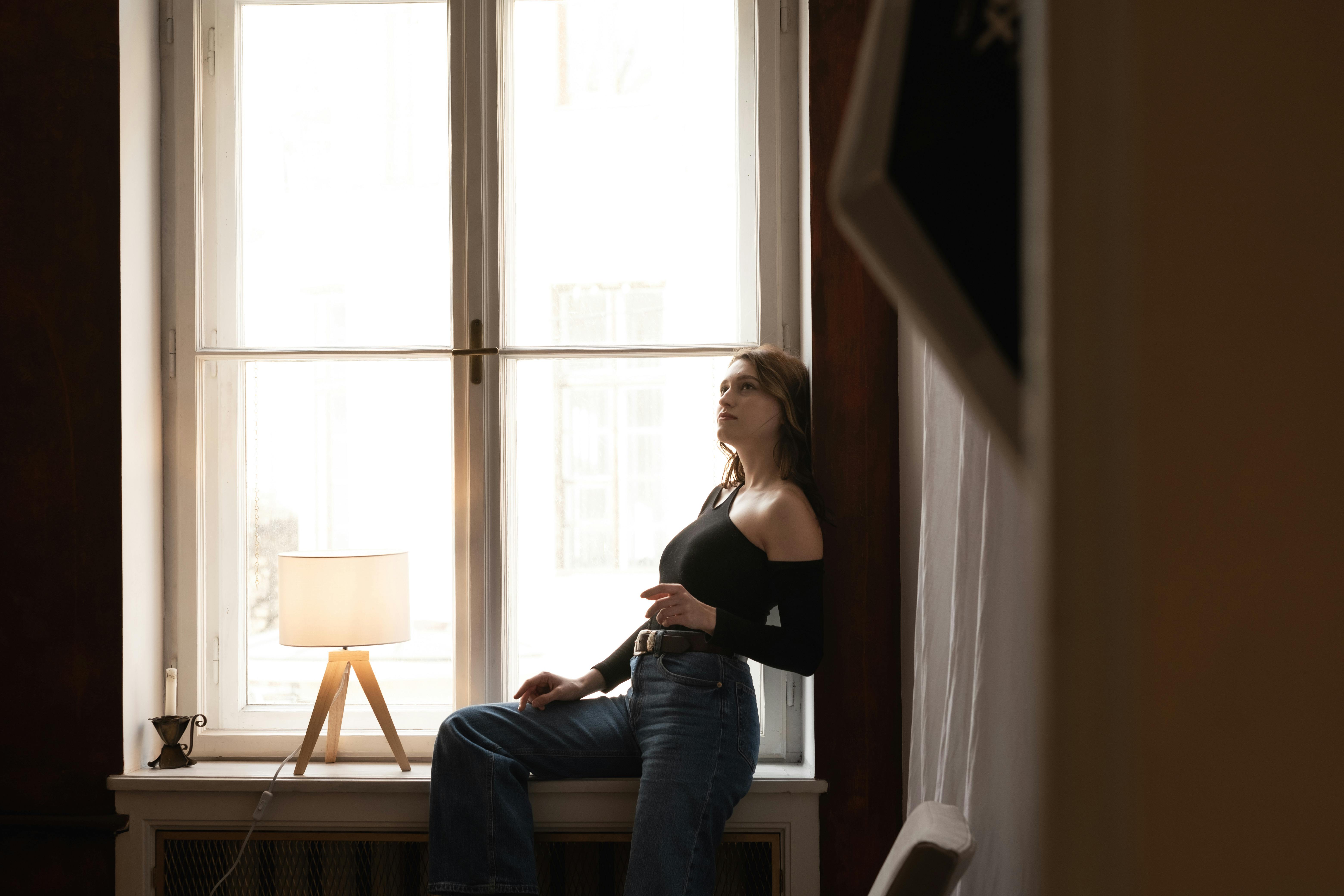 Woman sitting on a windowsill | Source: Pexels