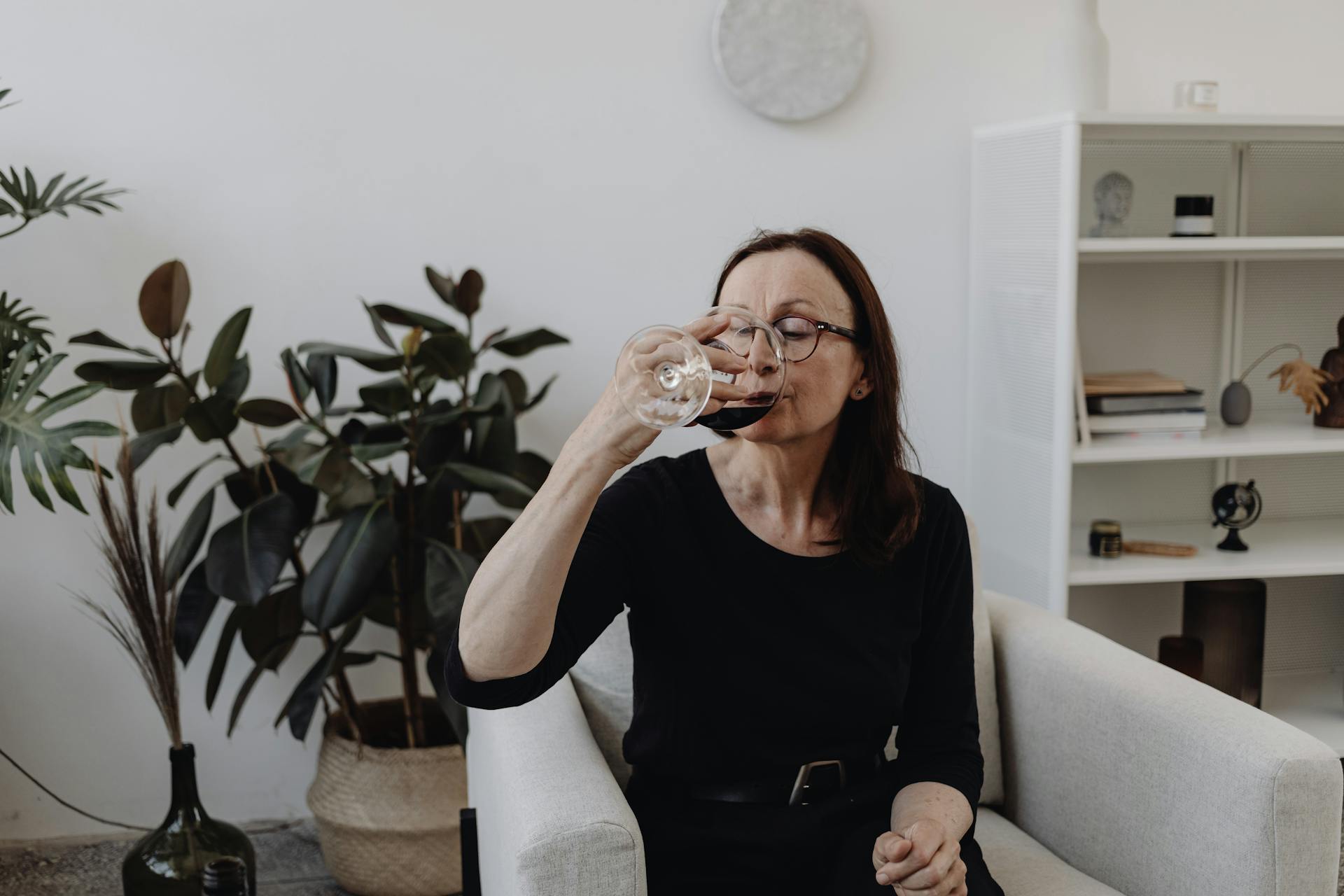 A senior woman drinking wine while sitting on the sofa | Source: Pexels