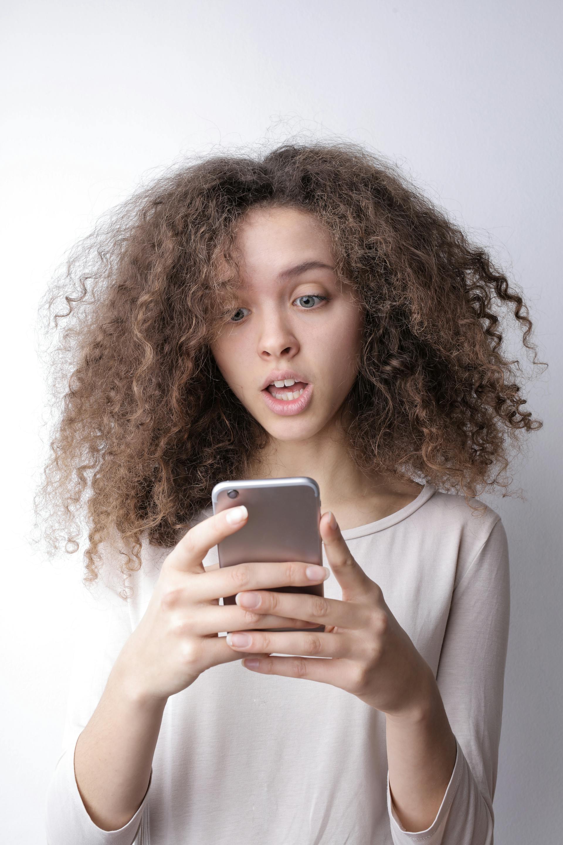 A surprised woman checking messages on her phone | Source: Pexels