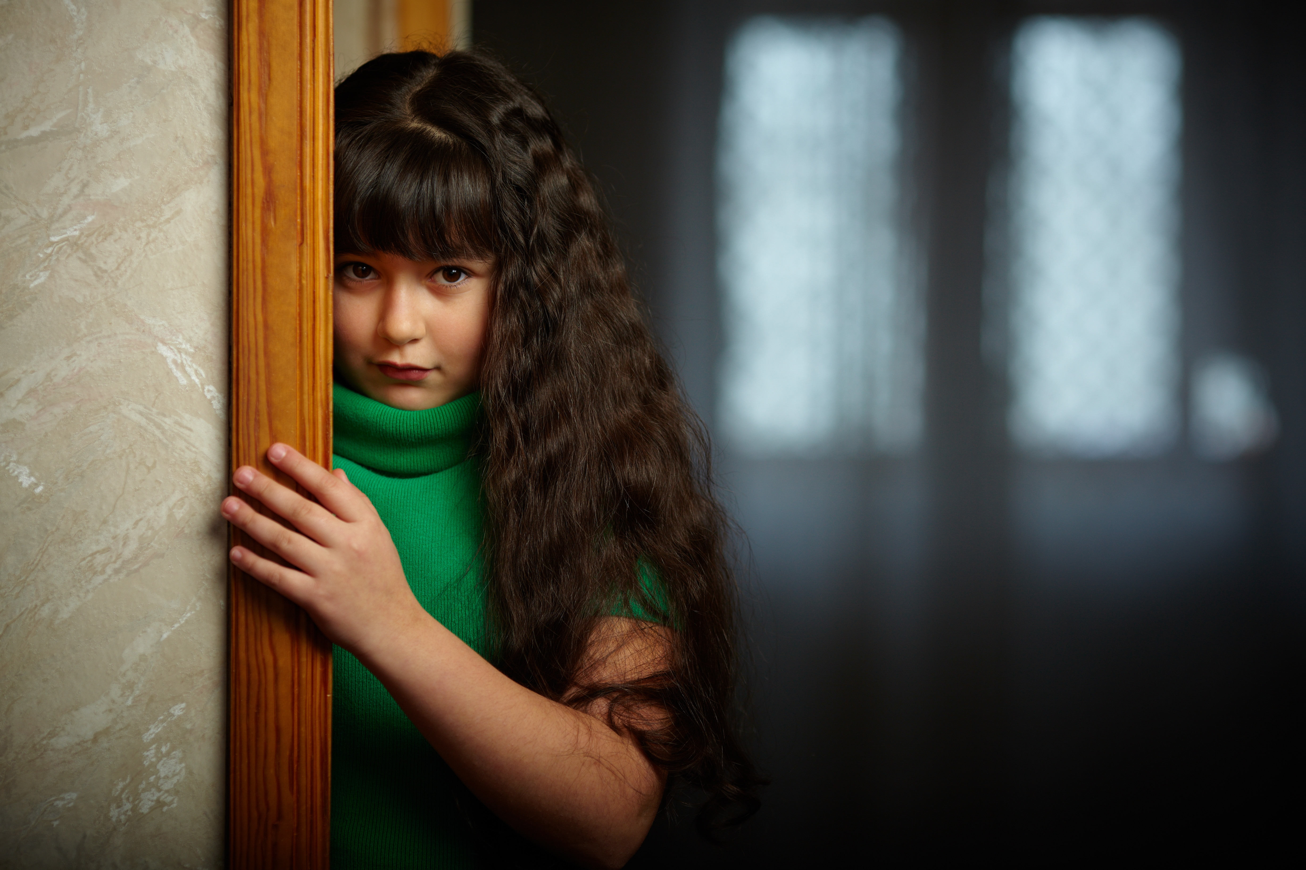 Sad girl near door | Source: Shutterstock.com