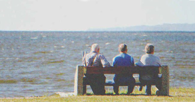 Three old men sitting on a bench by the sea. | Source: Shutterstock