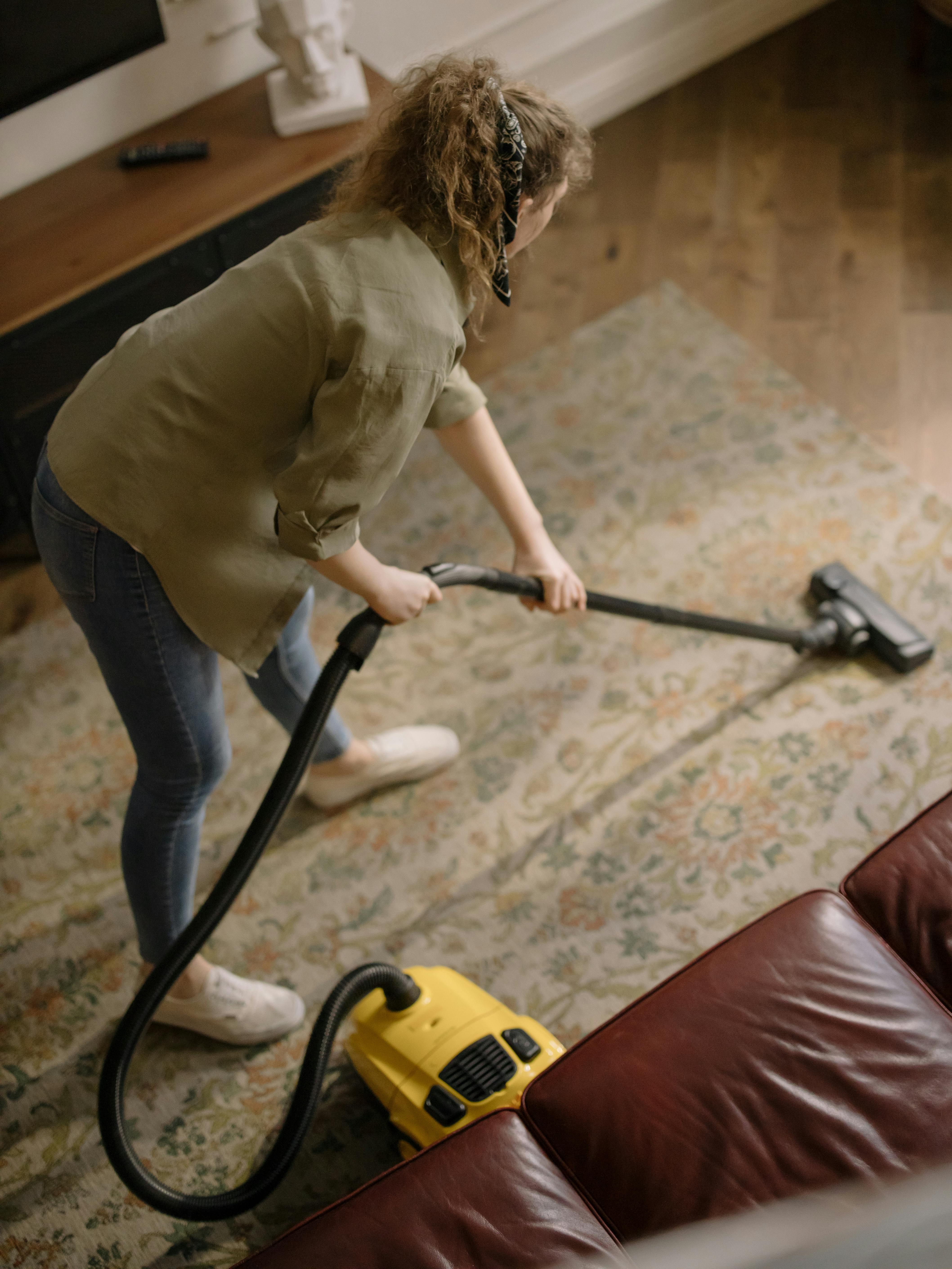 A woman using a vacuum cleaner on a carpet | Source: Pexels