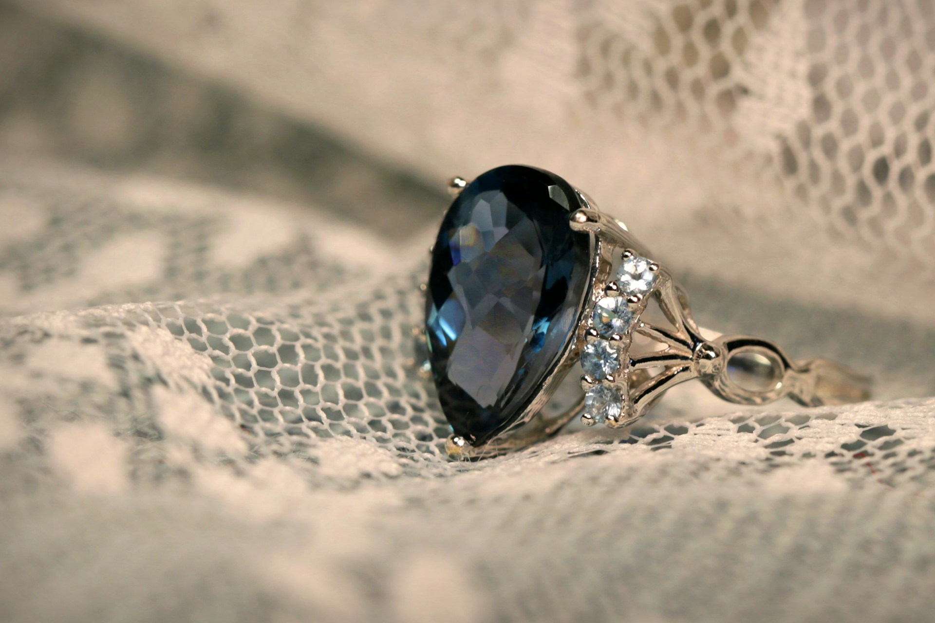 A stone-studded ring on a white lace cloth | Source: Unsplash