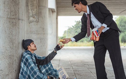 Photo of a kind-hearted businessman giving part of his big meat burger to a homeless man | Photo: Getty Images