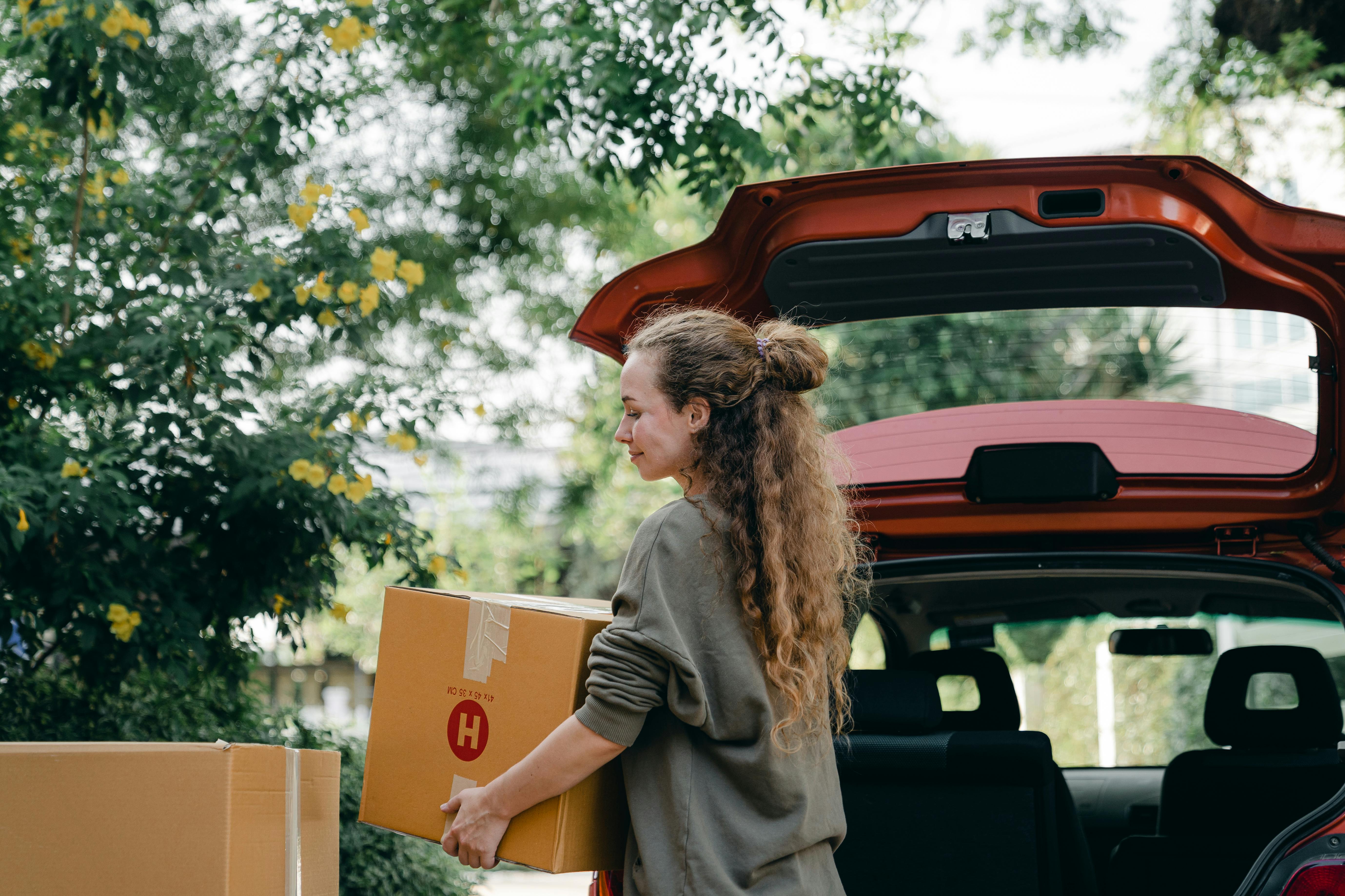 A happy woman loading boxes into her car | Source: Pexels