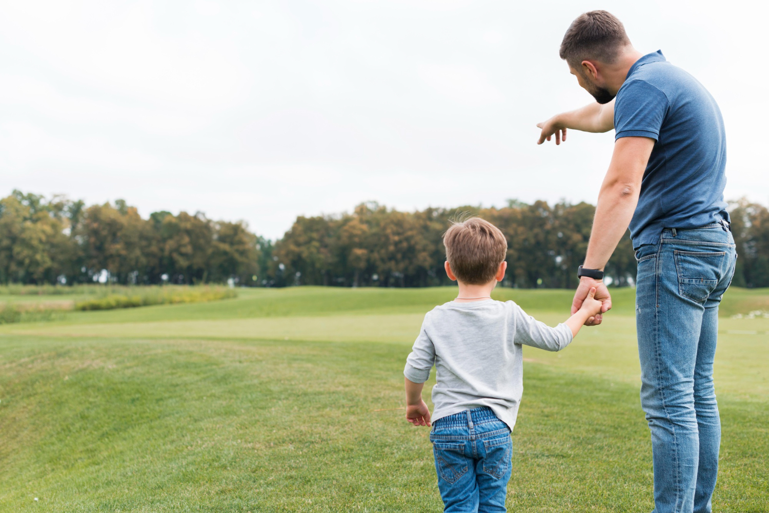A man holding a little boy's hand as they explore nature together | Source: Freepik